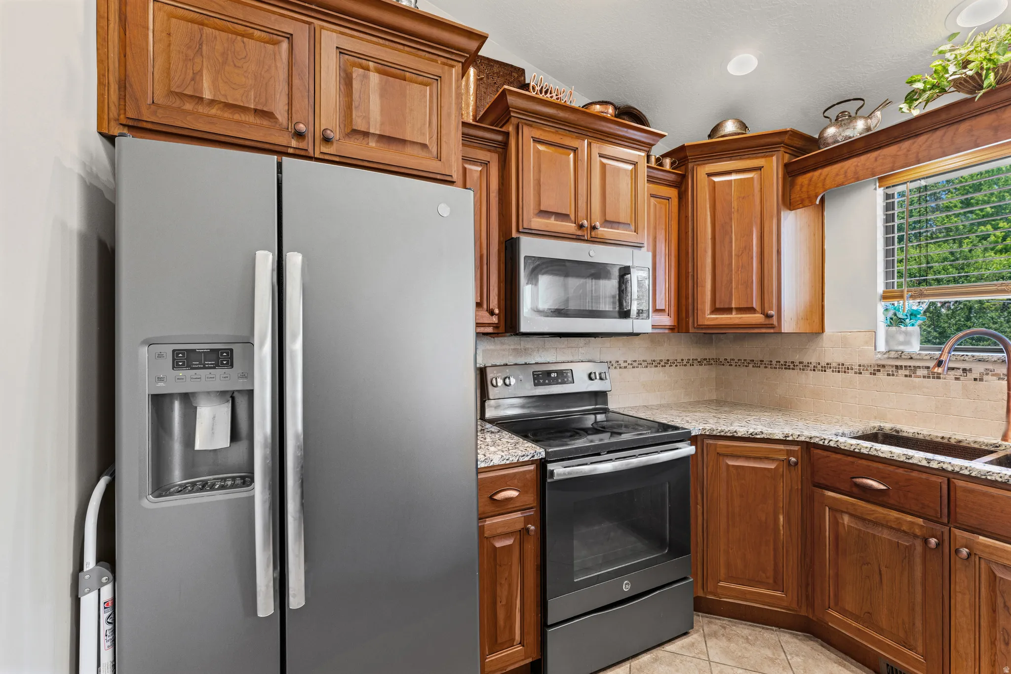 Kitchen featuring wood cabinetry, stainless steel appliances, speckled countertops, and a tiled backsplash