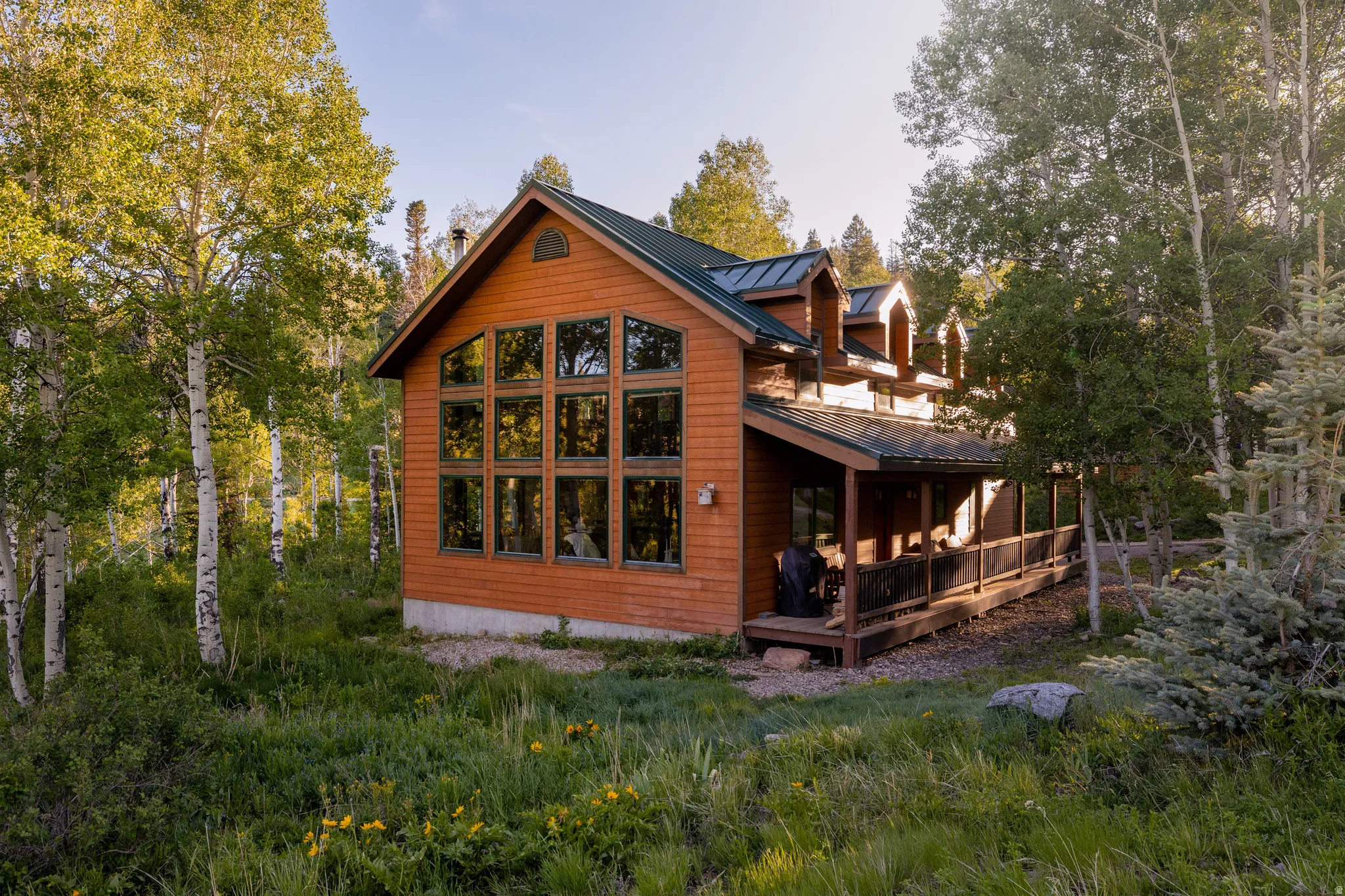 Wood-sided home with a green metal roof and a prominent wall of windows