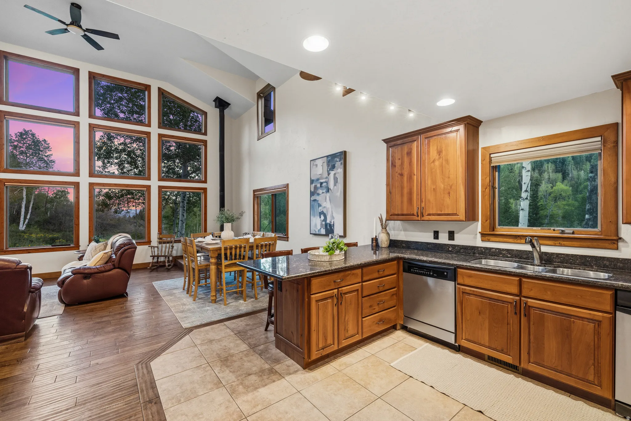 Open-concept living space featuring a high vaulted ceiling, a full wall of rectangular windows with wood framing, and wood-finish flooring