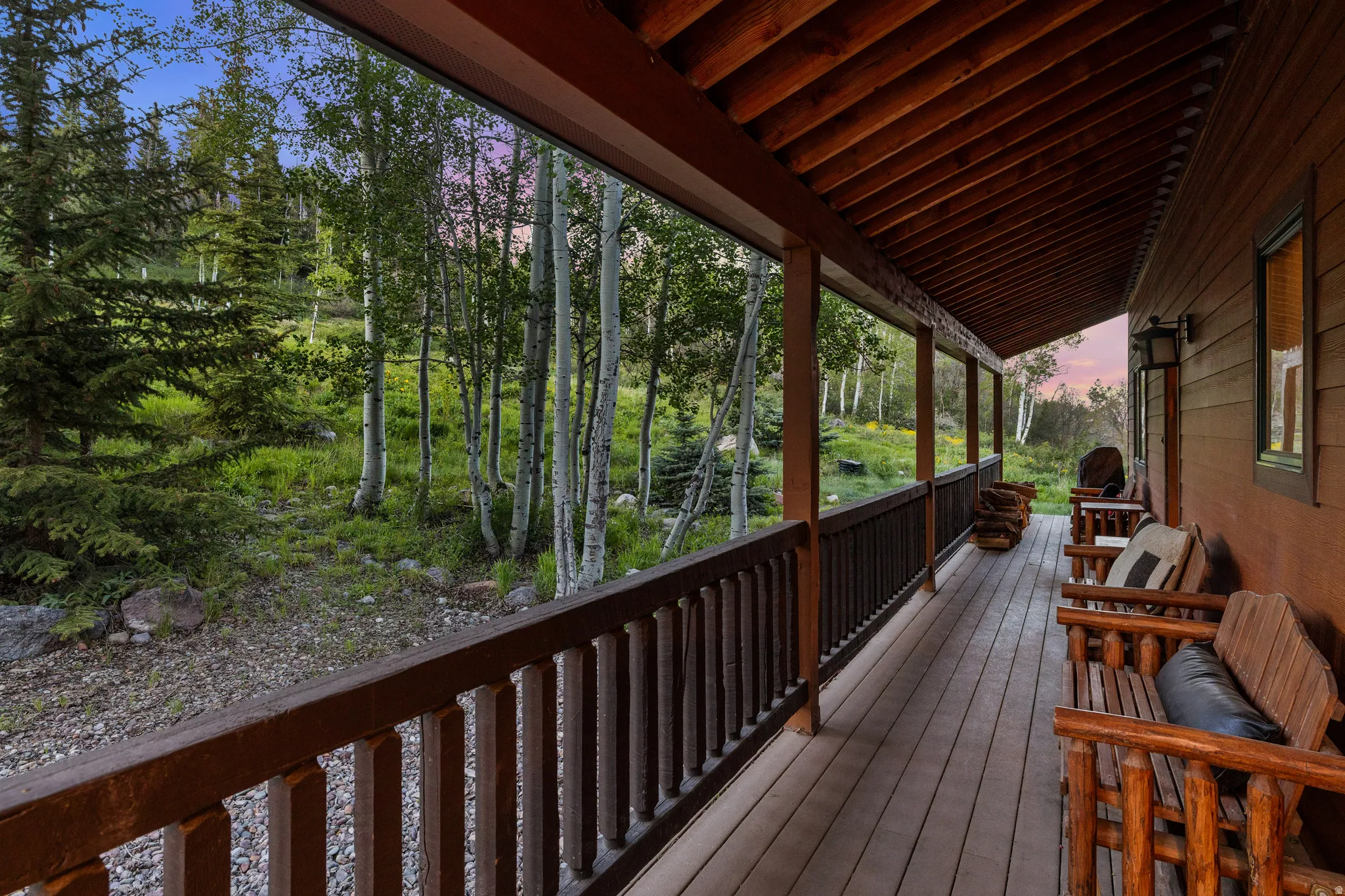 Expansive covered porch featuring wood-finish decking, dark wood railings, and exposed wood ceiling beams
