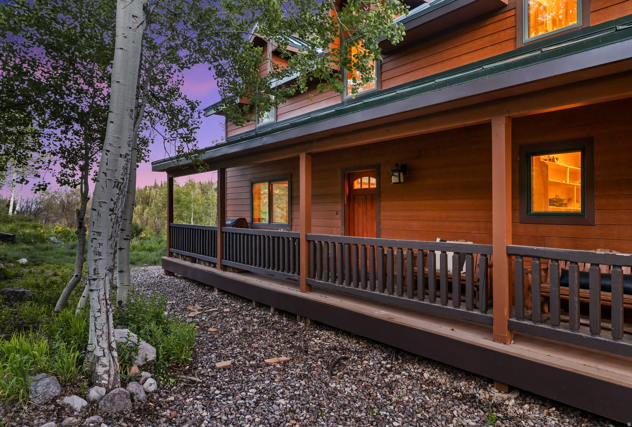 Wood-sided exterior featuring an expansive covered porch with dark wood railings and posts