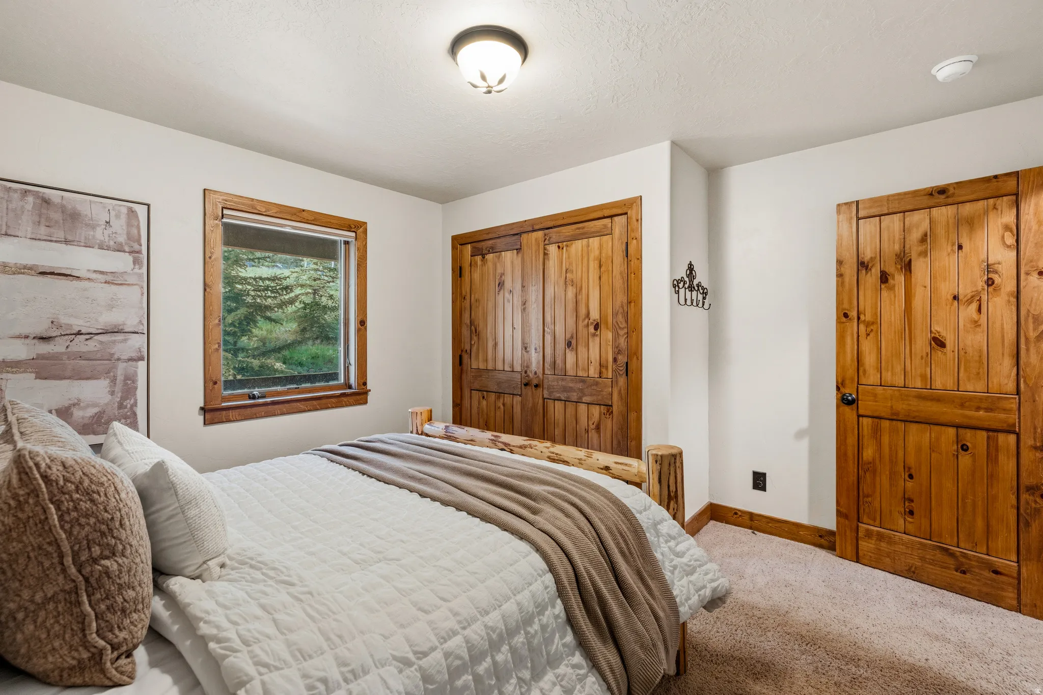 Bedroom featuring wood-finish doors and window trim, a carpeted floor, and a window overlooking exterior greenery