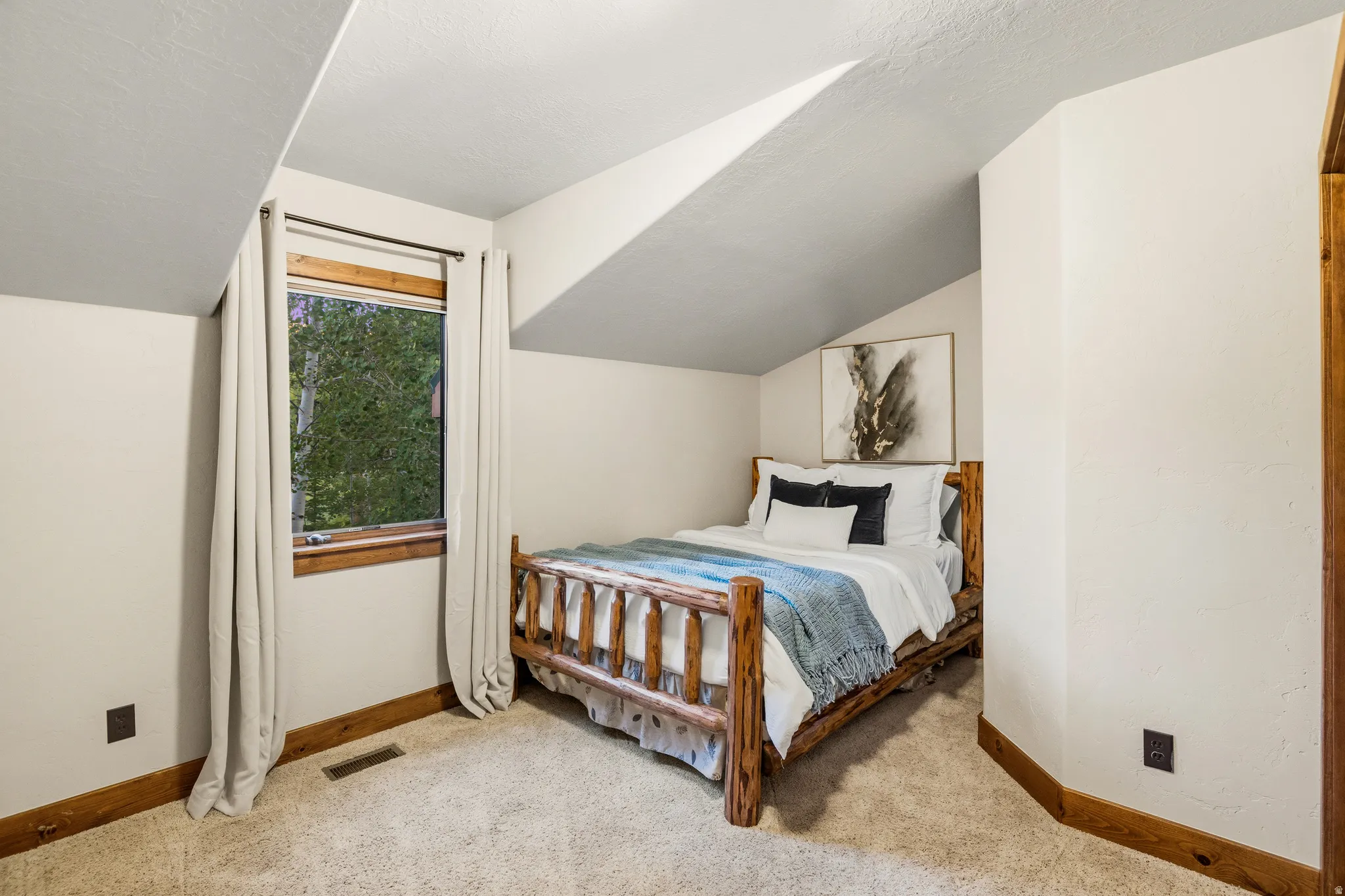 Carpeted room featuring a window with wood trim, sloped ceiling, and wood baseboards