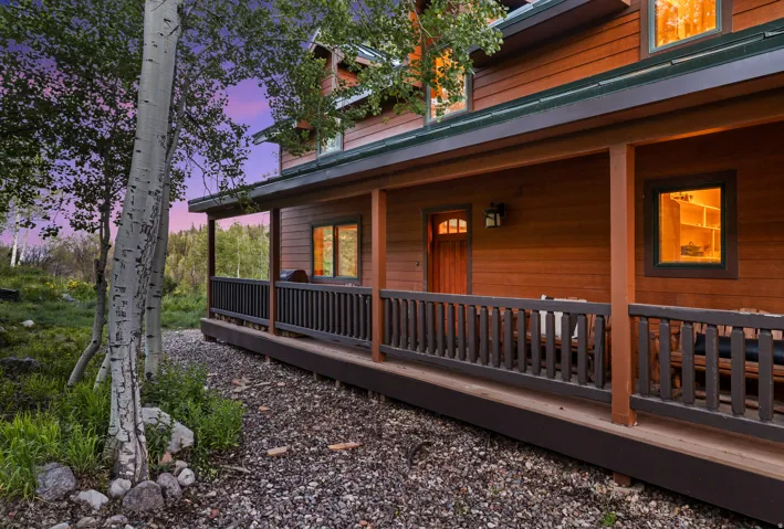 Wood-sided exterior featuring an expansive covered porch with dark wood railings and posts