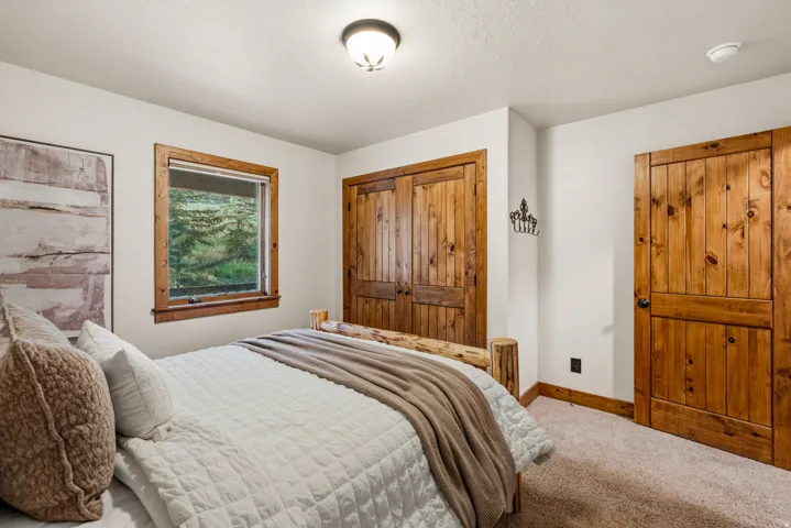 Bedroom featuring wood-finish doors and window trim, a carpeted floor, and a window overlooking exterior greenery