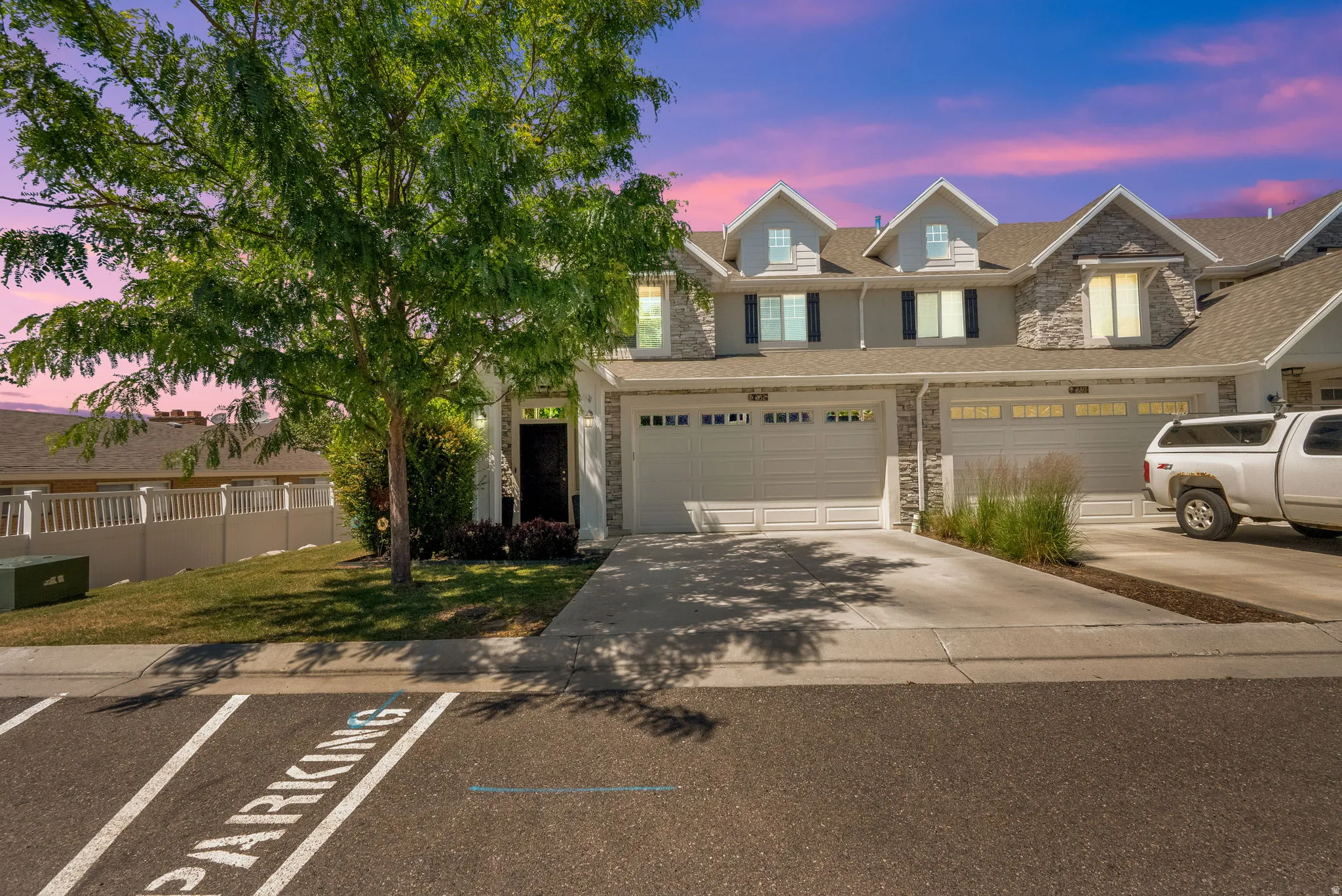 Modern townhome exterior featuring light-colored siding, stone accents, and multiple gabled dormers