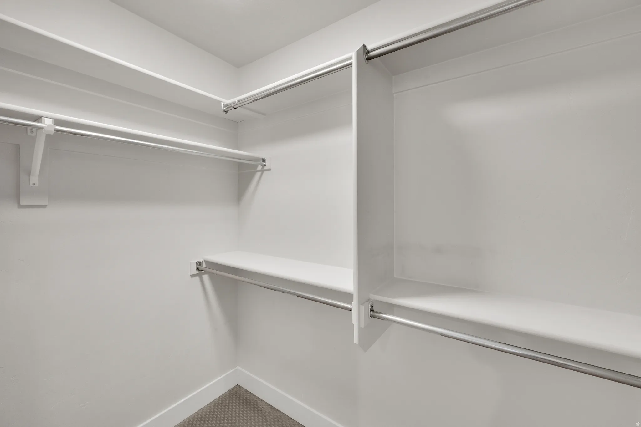 Custom closet system featuring multiple white shelves and chrome hanging rods