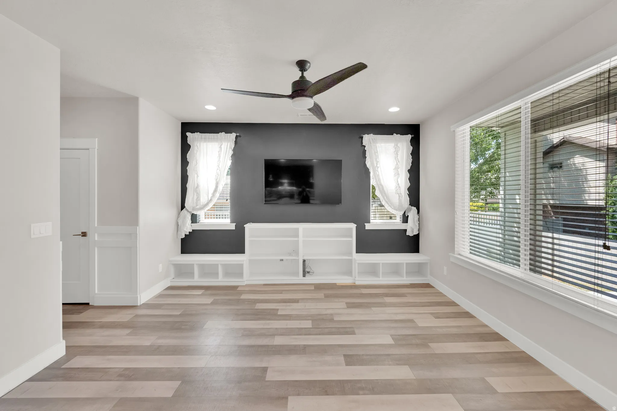 Spacious room with wood-finish flooring, a contemporary ceiling fan, and recessed lighting