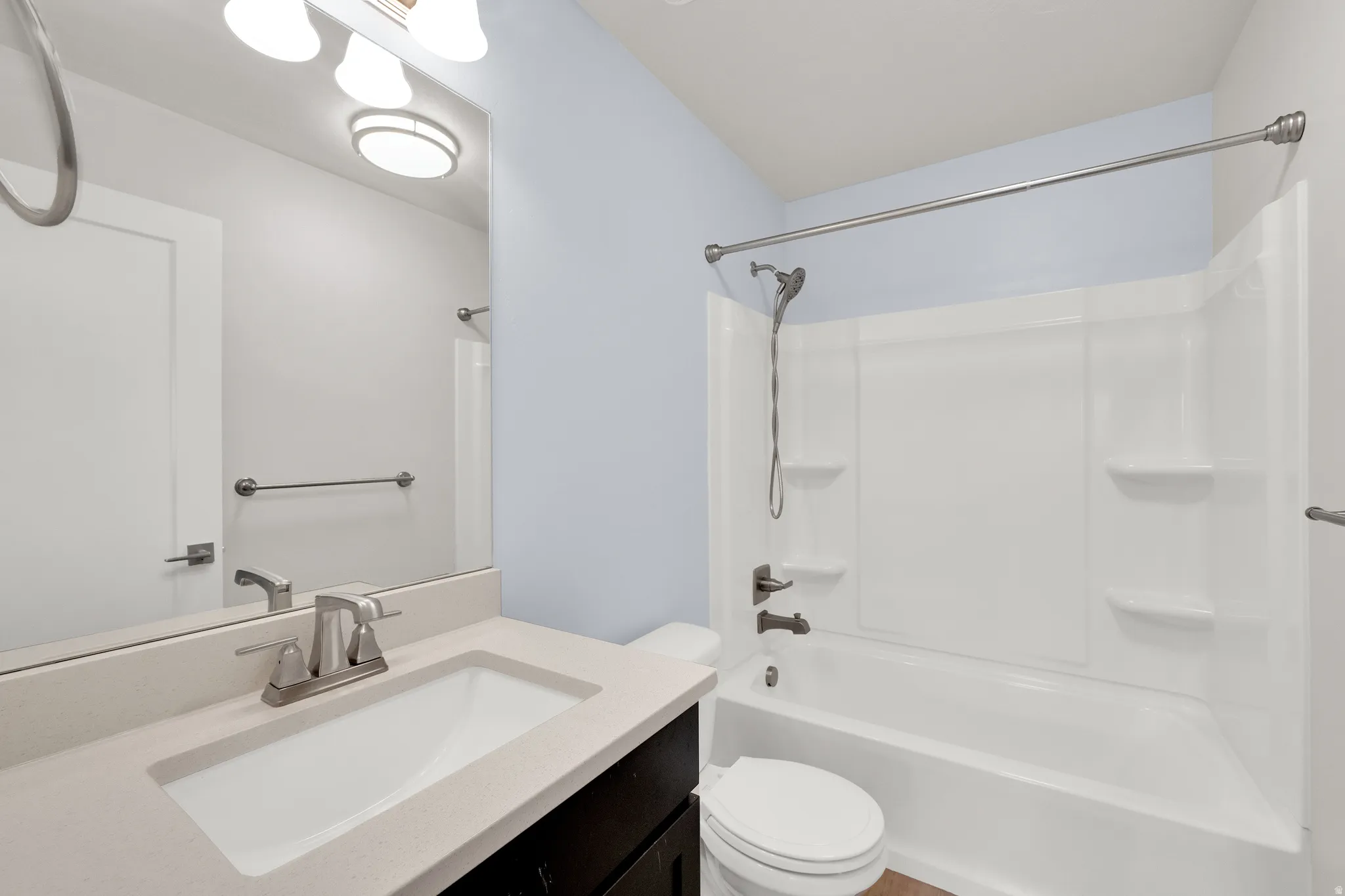 Bathroom featuring a white integrated sink, light-toned countertop, dark wood-finish vanity, and brushed nickel fixtures