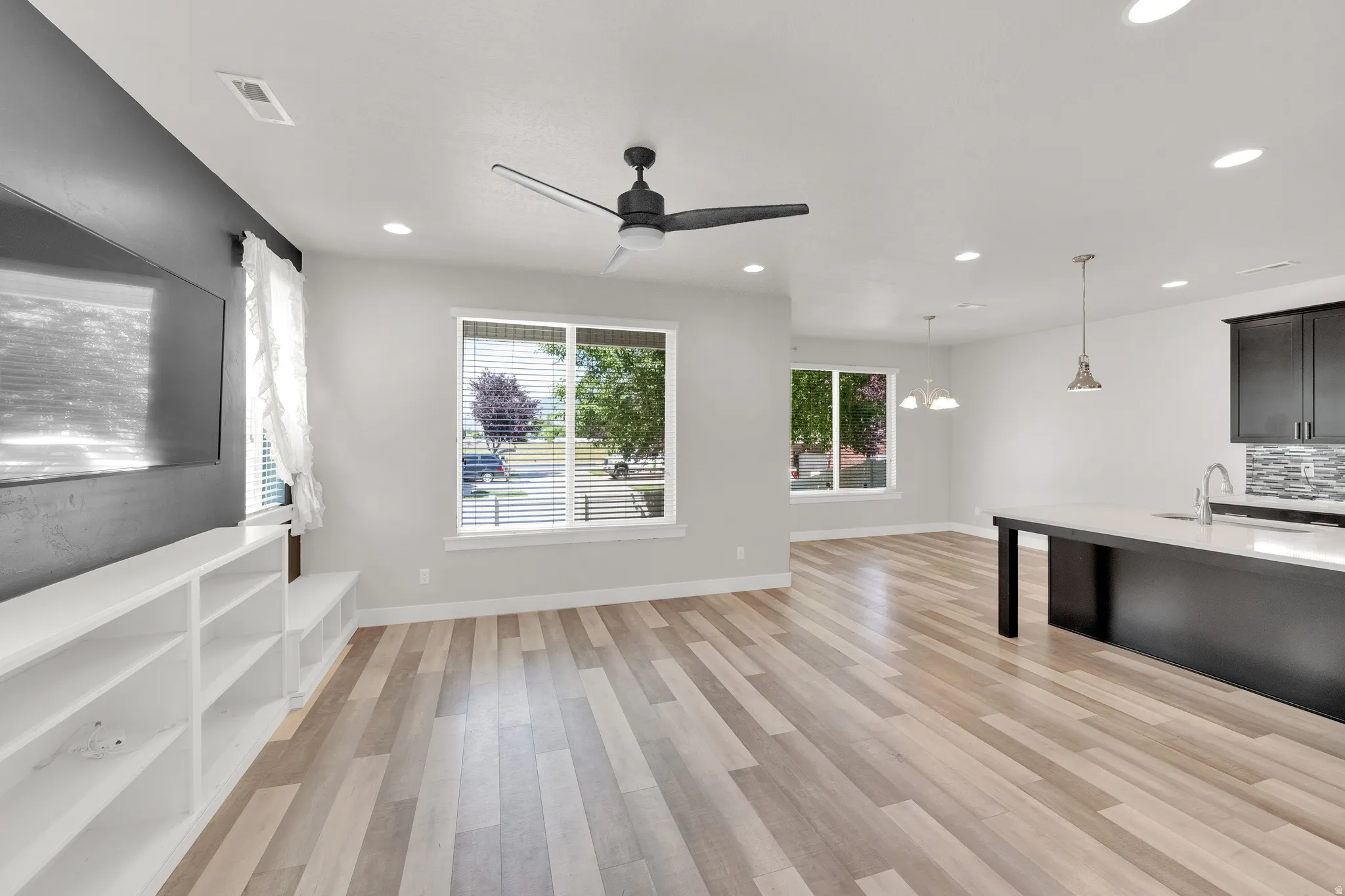 Open-concept living area featuring wood-finish flooring, recessed lighting, and a modern ceiling fan