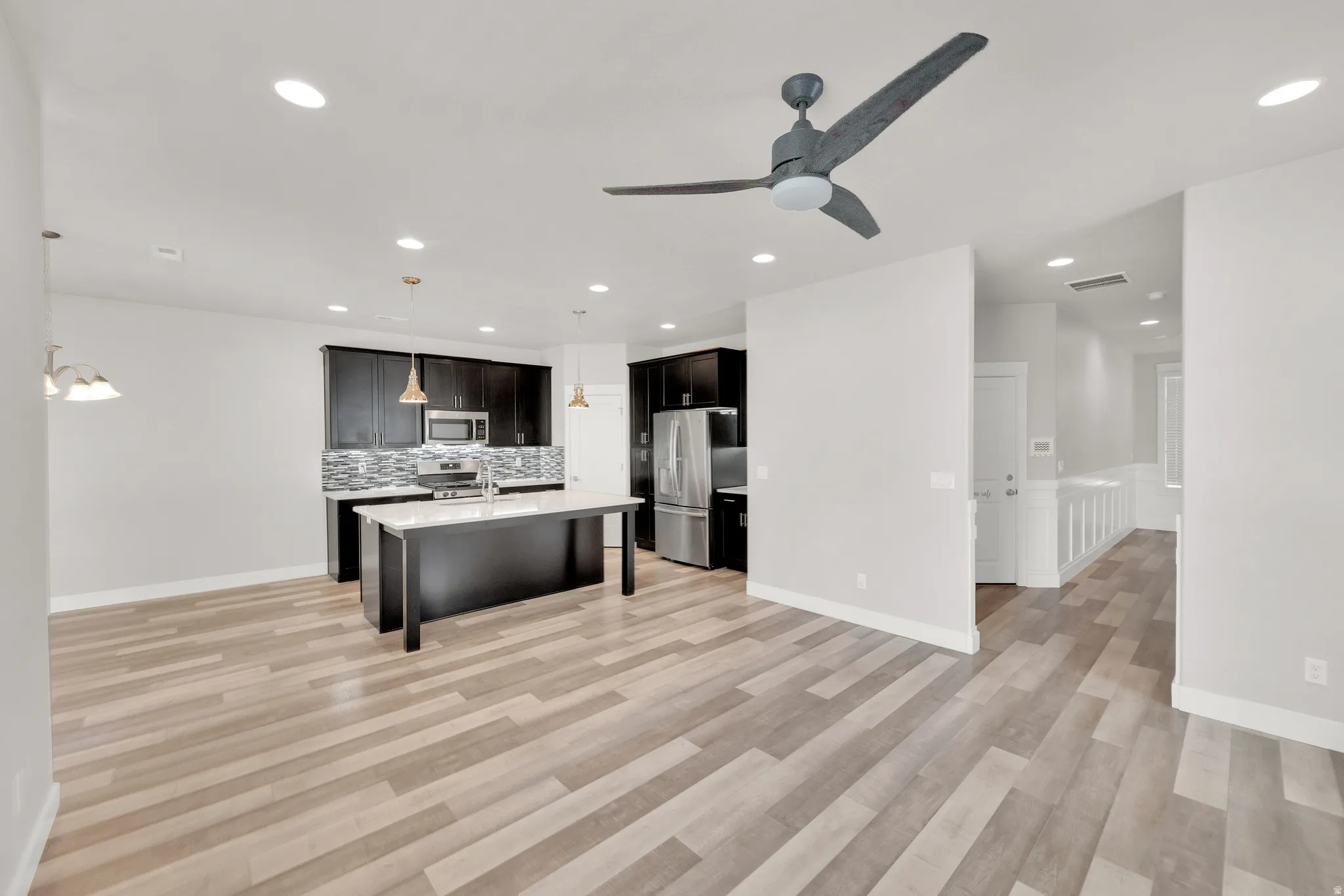 Open-concept living space featuring wood-finish flooring, recessed lighting, and a contemporary ceiling fan