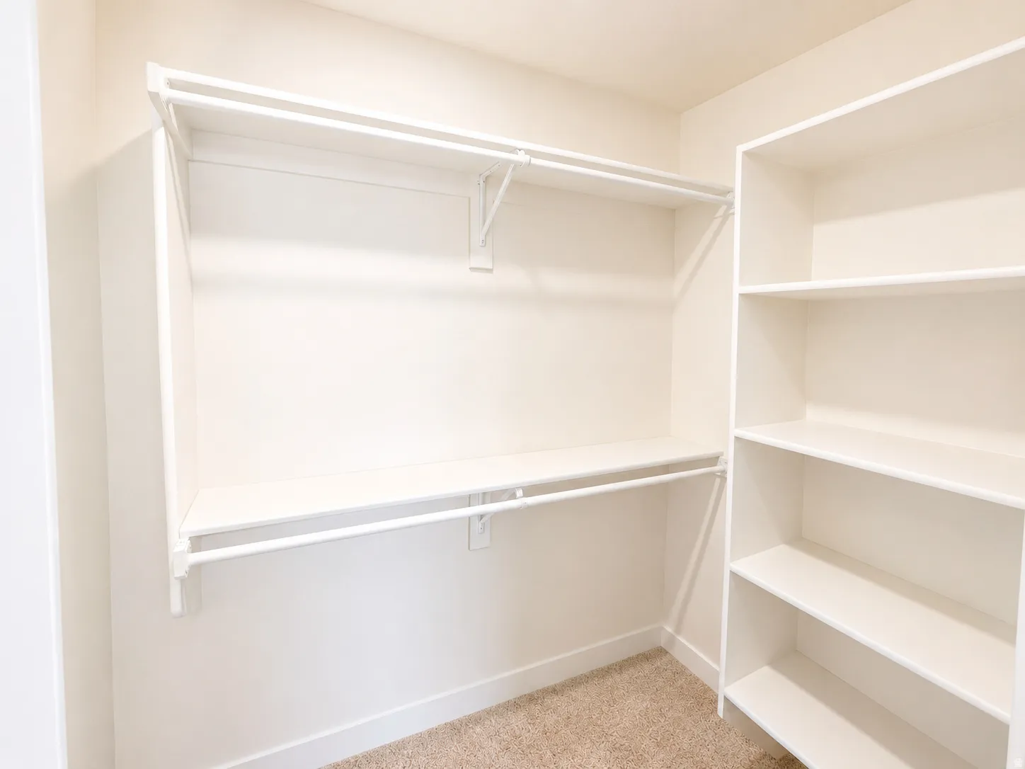 Walk-in closet featuring built-in shelving, two hanging rods, and neutral carpet