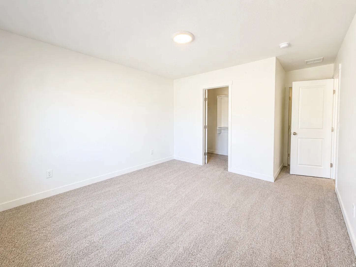 Carpeted room featuring a ceiling-mounted light fixture, white walls, and white baseboards