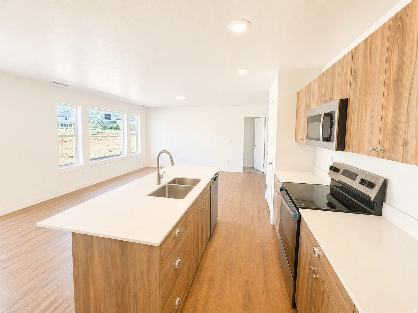 Kitchen featuring wood-finish cabinetry, stainless steel appliances, a white solid-surface countertop, and an island with an integrated double sink