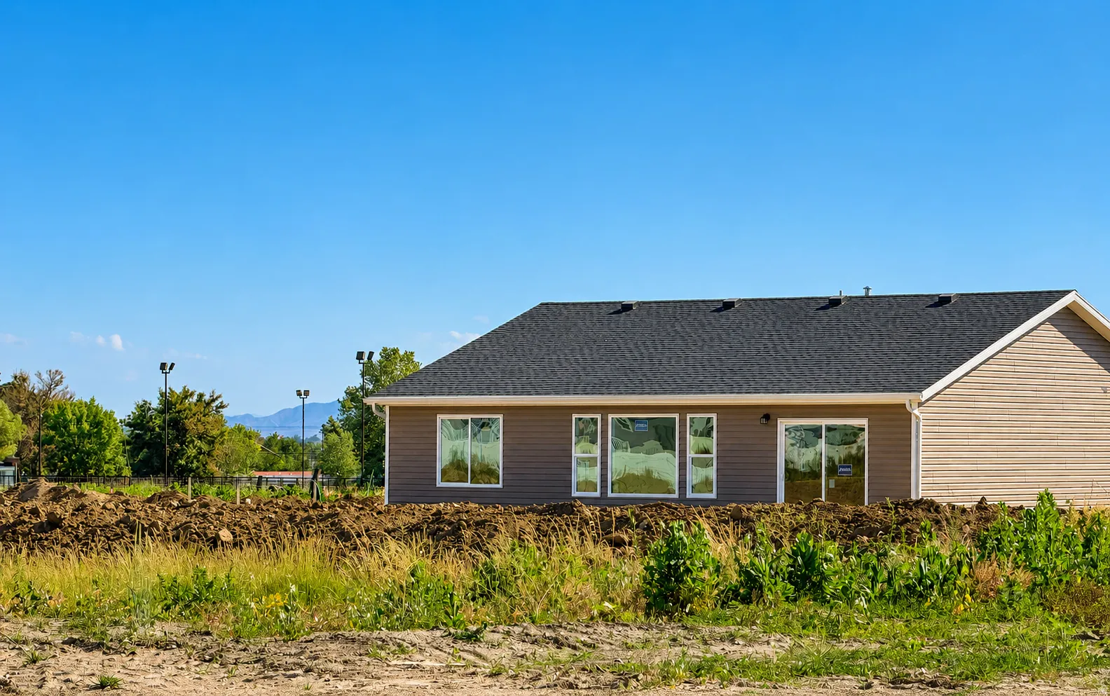 Newly constructed property featuring a dark shingle roof and light brown siding