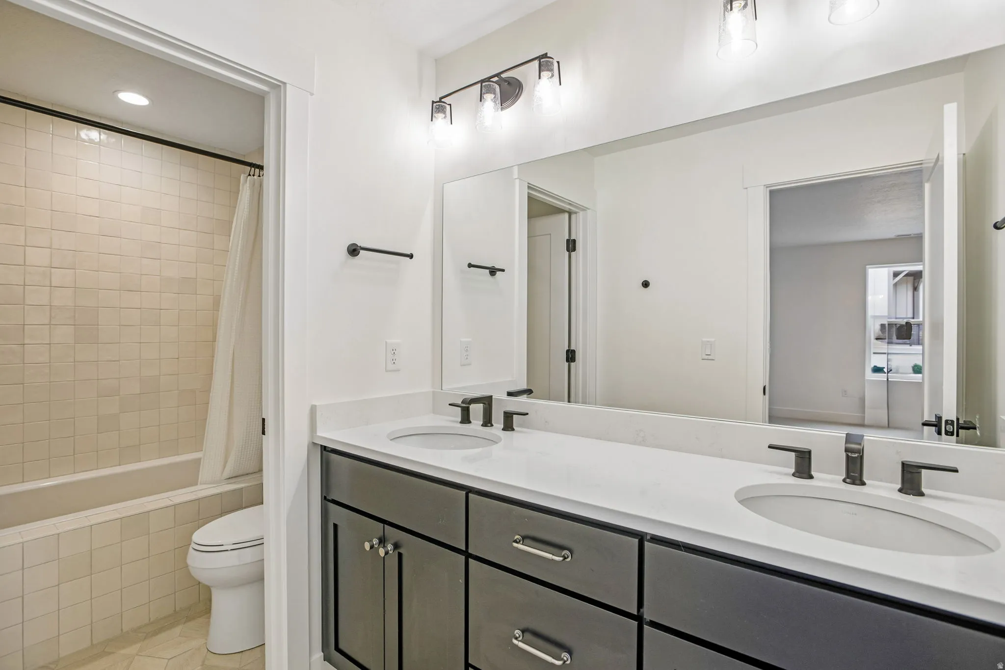 Bathroom featuring a double vanity with stone countertops, undermount sinks, and dark cabinetry