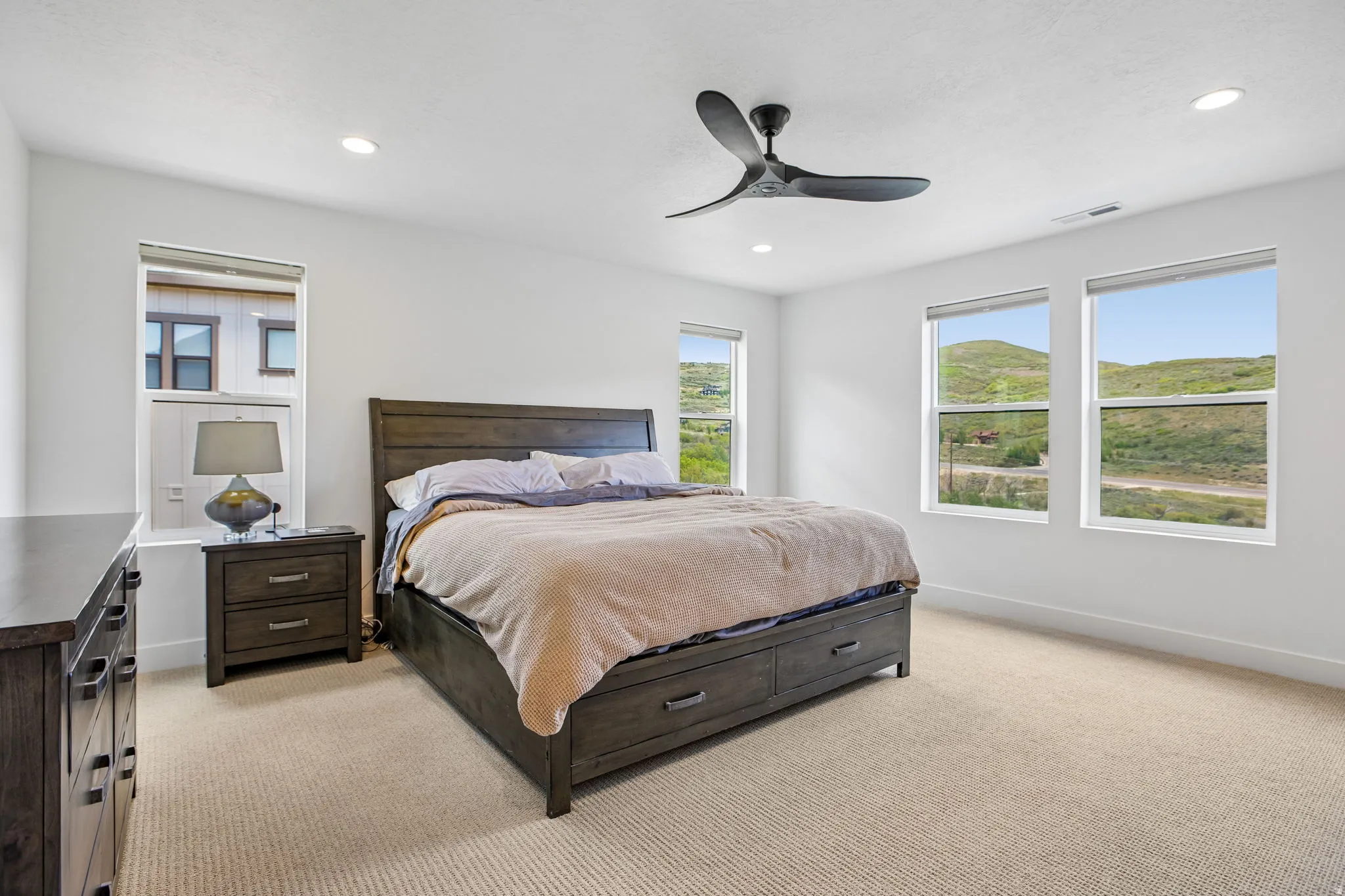 Carpeted room featuring a ceiling fan with integrated lighting, recessed lighting, and multiple windows