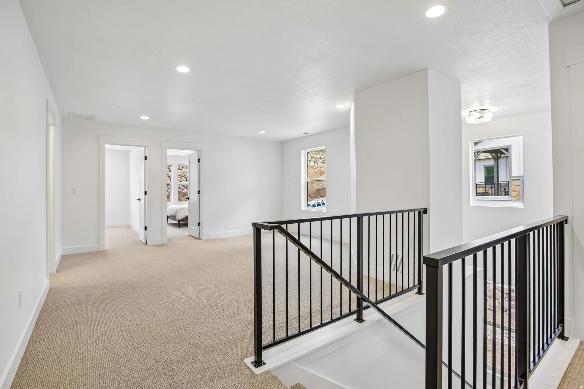 Spacious upper-level landing featuring neutral carpeting, white walls, and recessed lighting