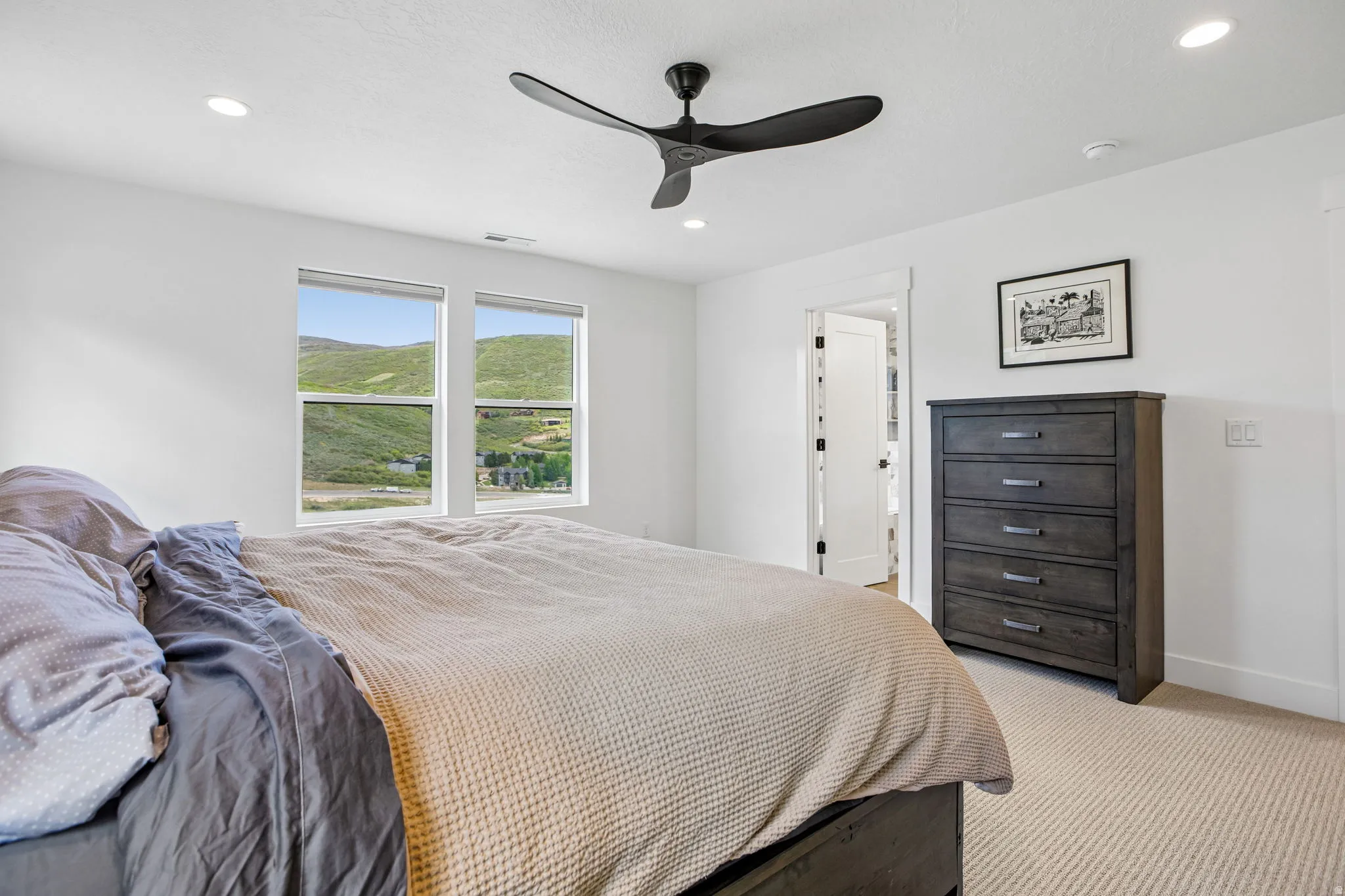 Bright room featuring two large windows, a ceiling fan with integrated lighting, recessed lighting, and neutral carpeting