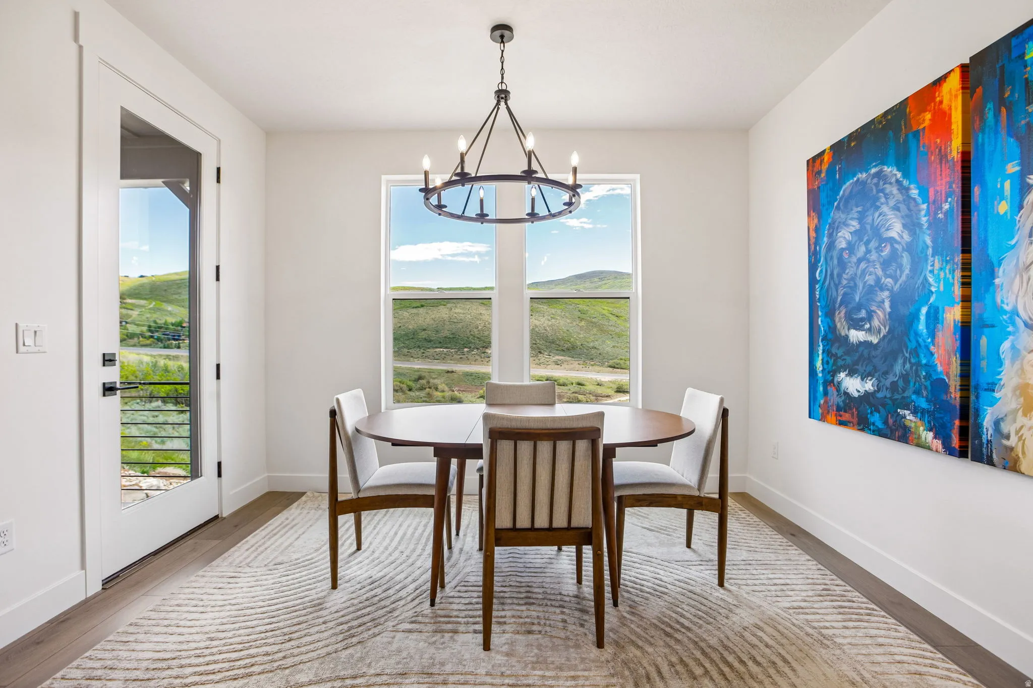 Dining space featuring wood-finish flooring, a contemporary chandelier, and ample natural light