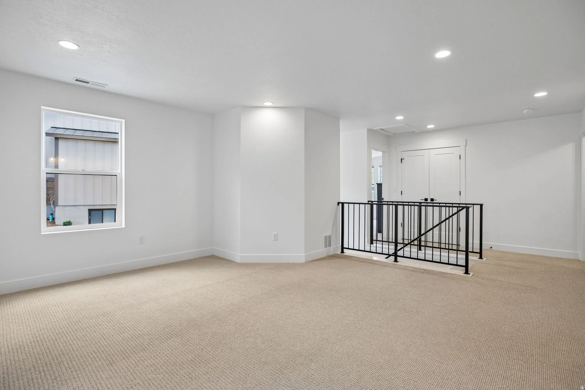 Open-concept room featuring neutral carpeting, a large window, and recessed lighting