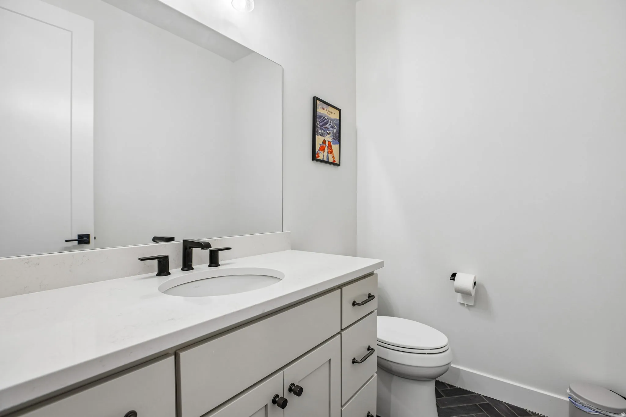 Bathroom featuring a vanity with a white countertop, an undermount sink, and matte black fixtures