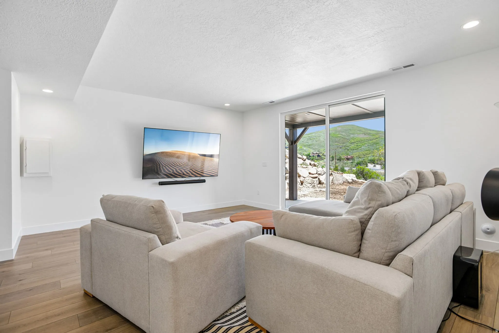 Spacious living area featuring wood-finish flooring, recessed lighting, and a large sliding glass door