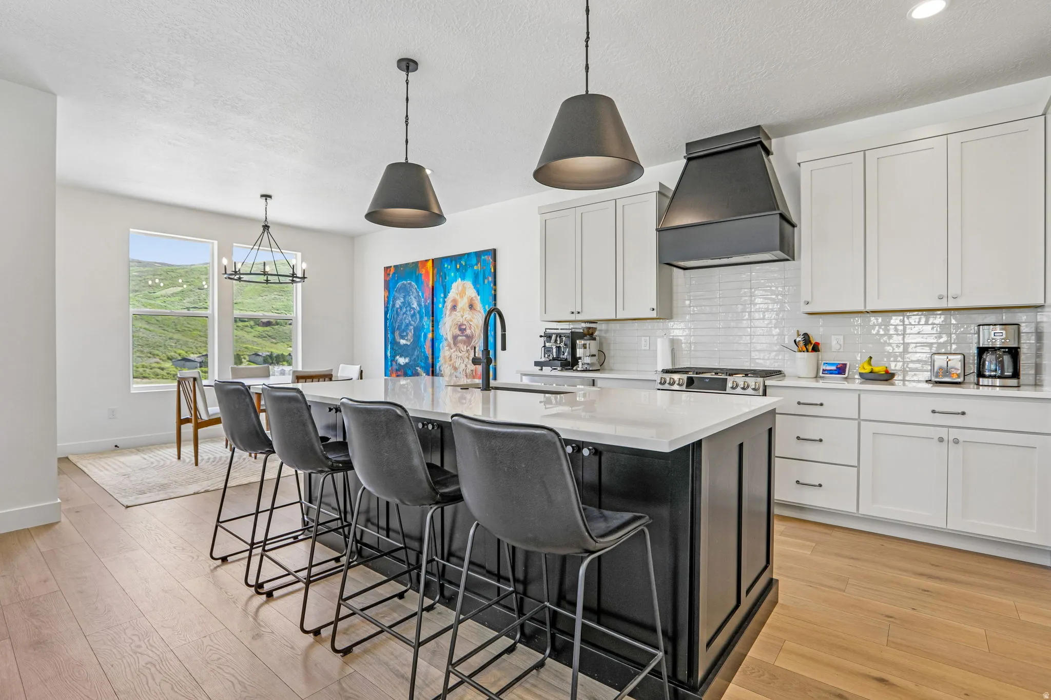 Spacious kitchen featuring a large central island with seating, white shaker cabinetry, white subway tile backsplash, and wood-finish flooring