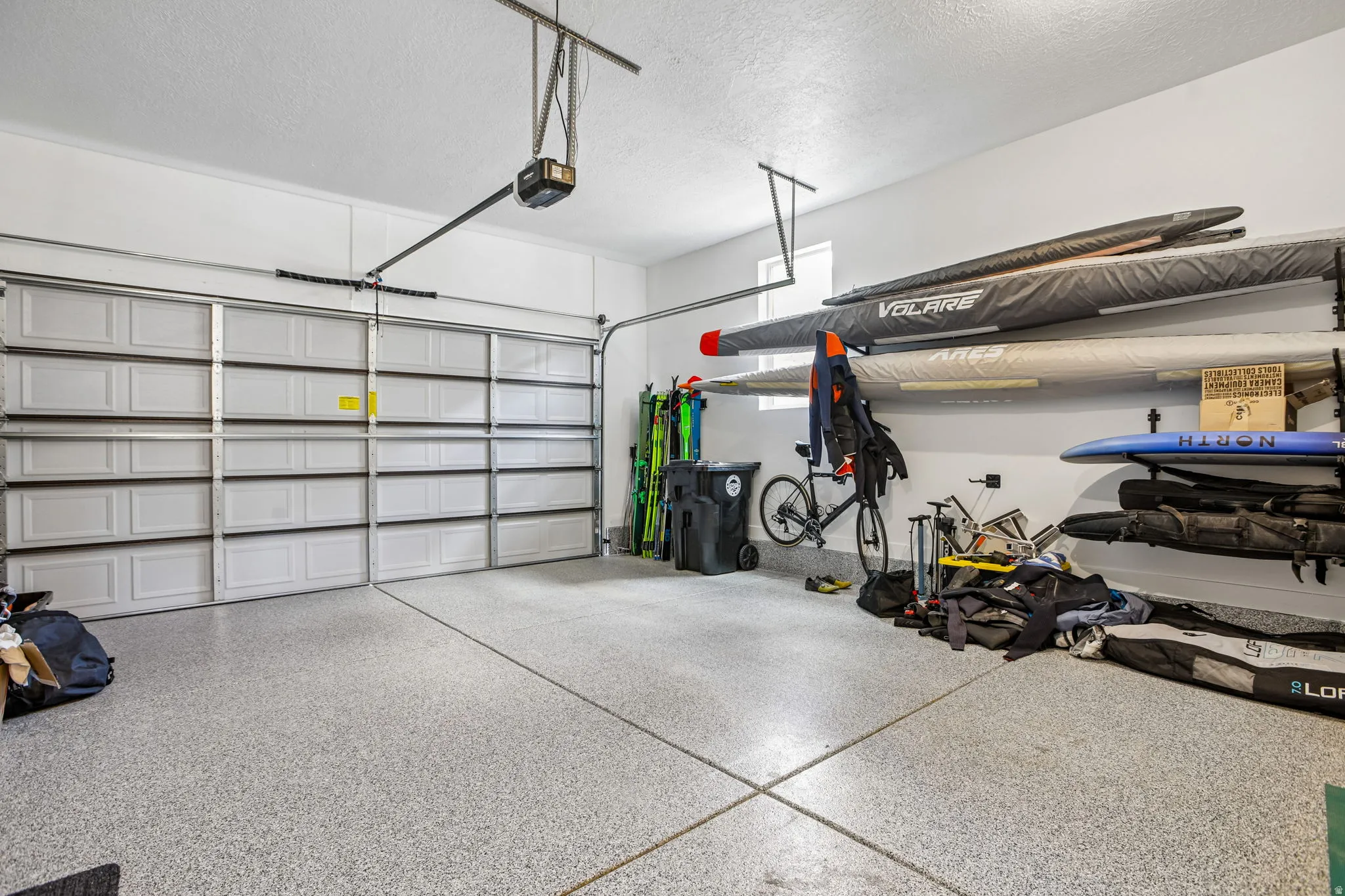 Spacious two-car garage featuring an epoxy-coated concrete floor, white panel garage doors, and overhead door openers