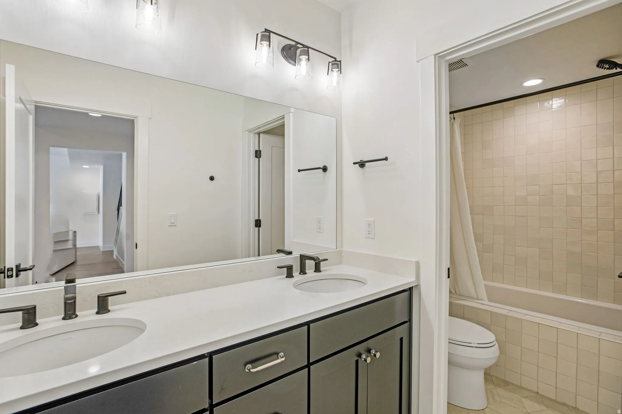 Dual vanity with a white countertop and undermount sinks, matte black fixtures, and dark cabinetry