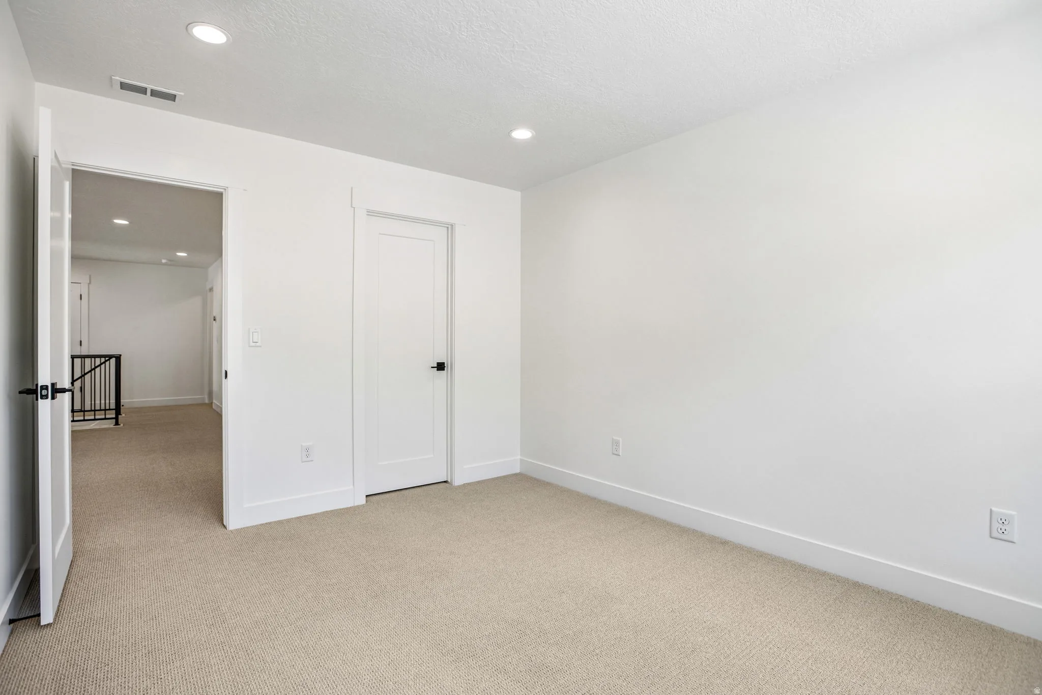 Carpeted room with recessed lighting and a solid core door