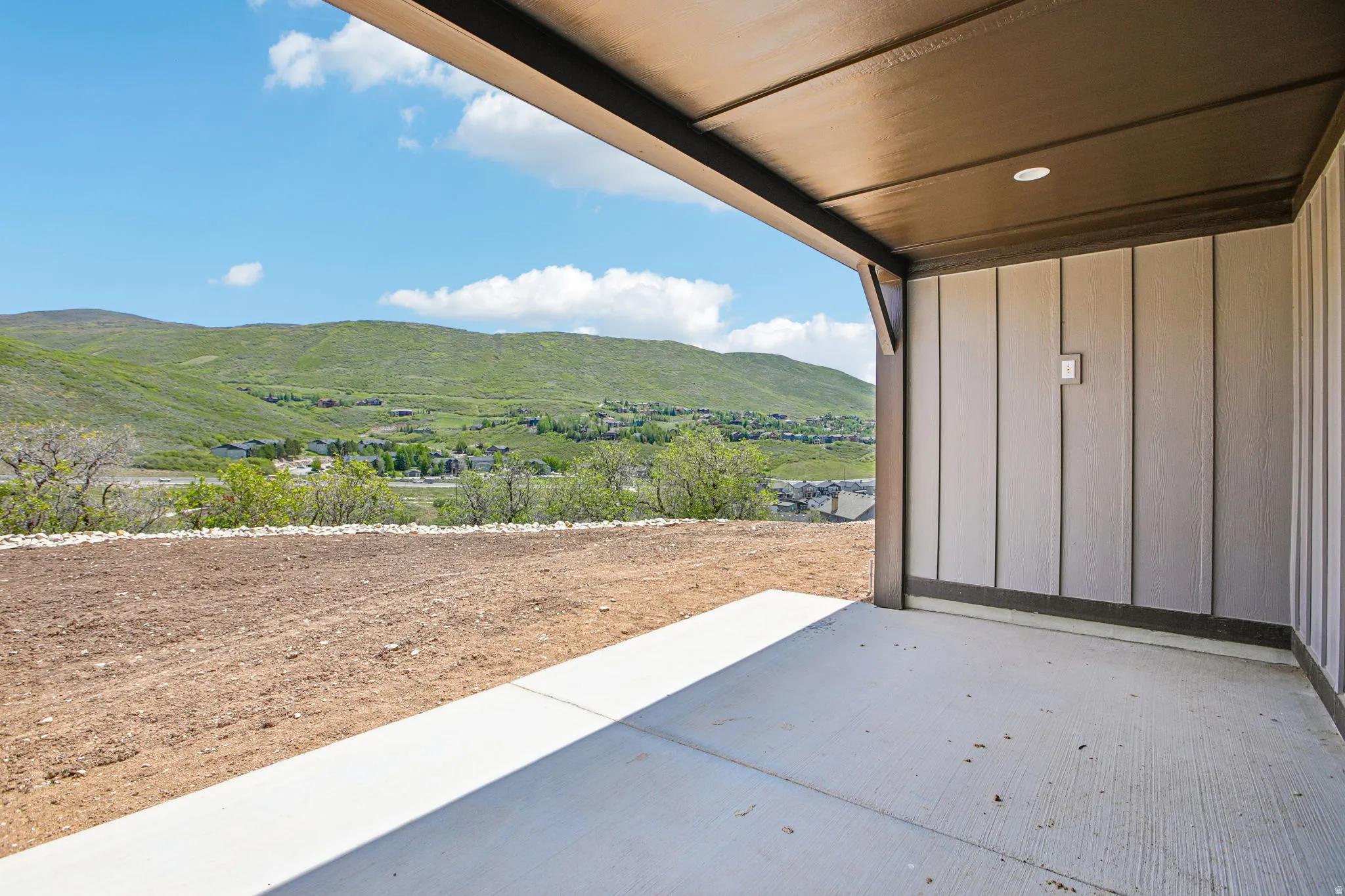 Covered patio with concrete flooring, recessed lighting, vertical panel siding, and a mountain backdrop