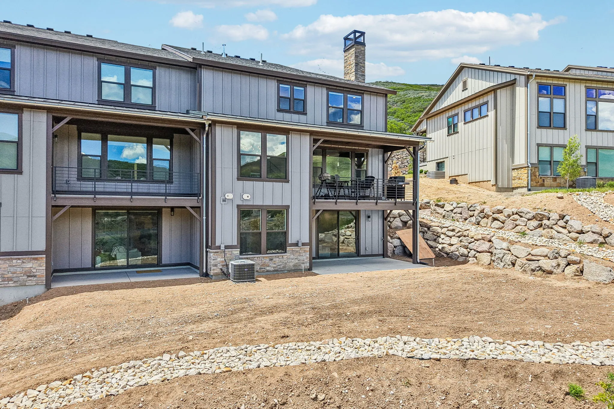 Modern multi-level exterior with vertical panel siding and stone accents