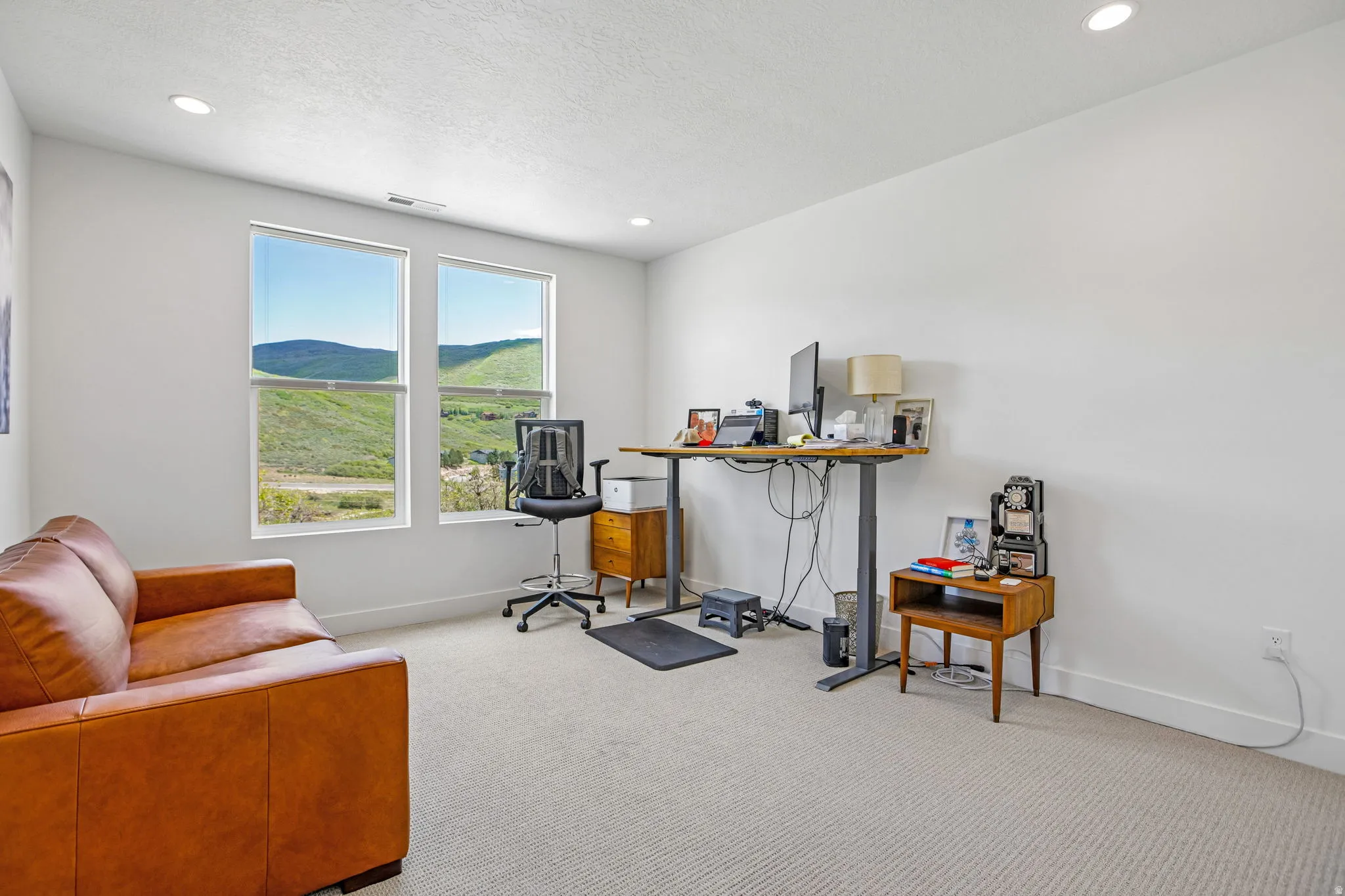 Bright interior space featuring two large vertical windows, recessed lighting, light-toned carpet, and white walls with white baseboards