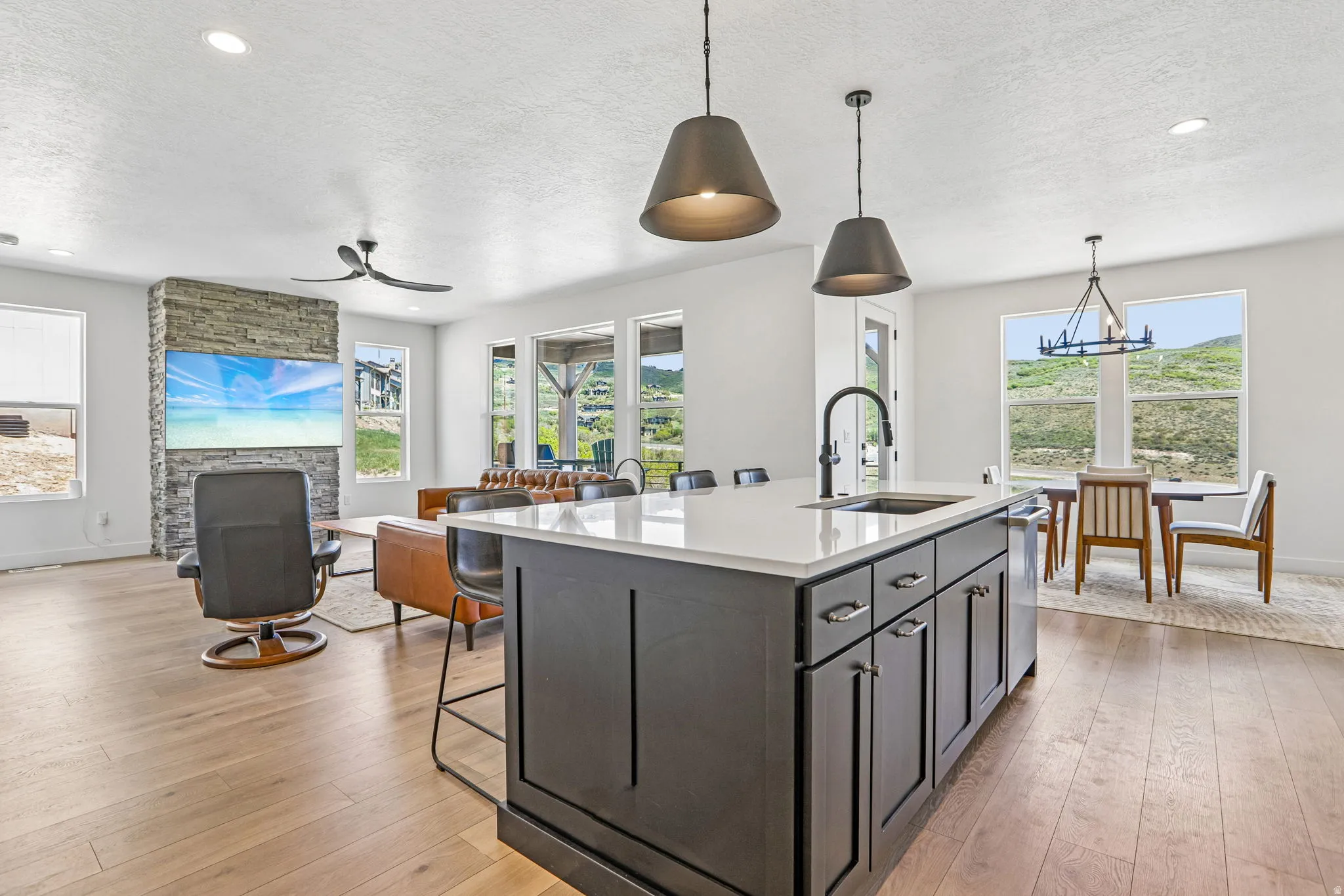Kitchen island featuring dark cabinetry, a white countertop, and an integrated sink with a matte black faucet