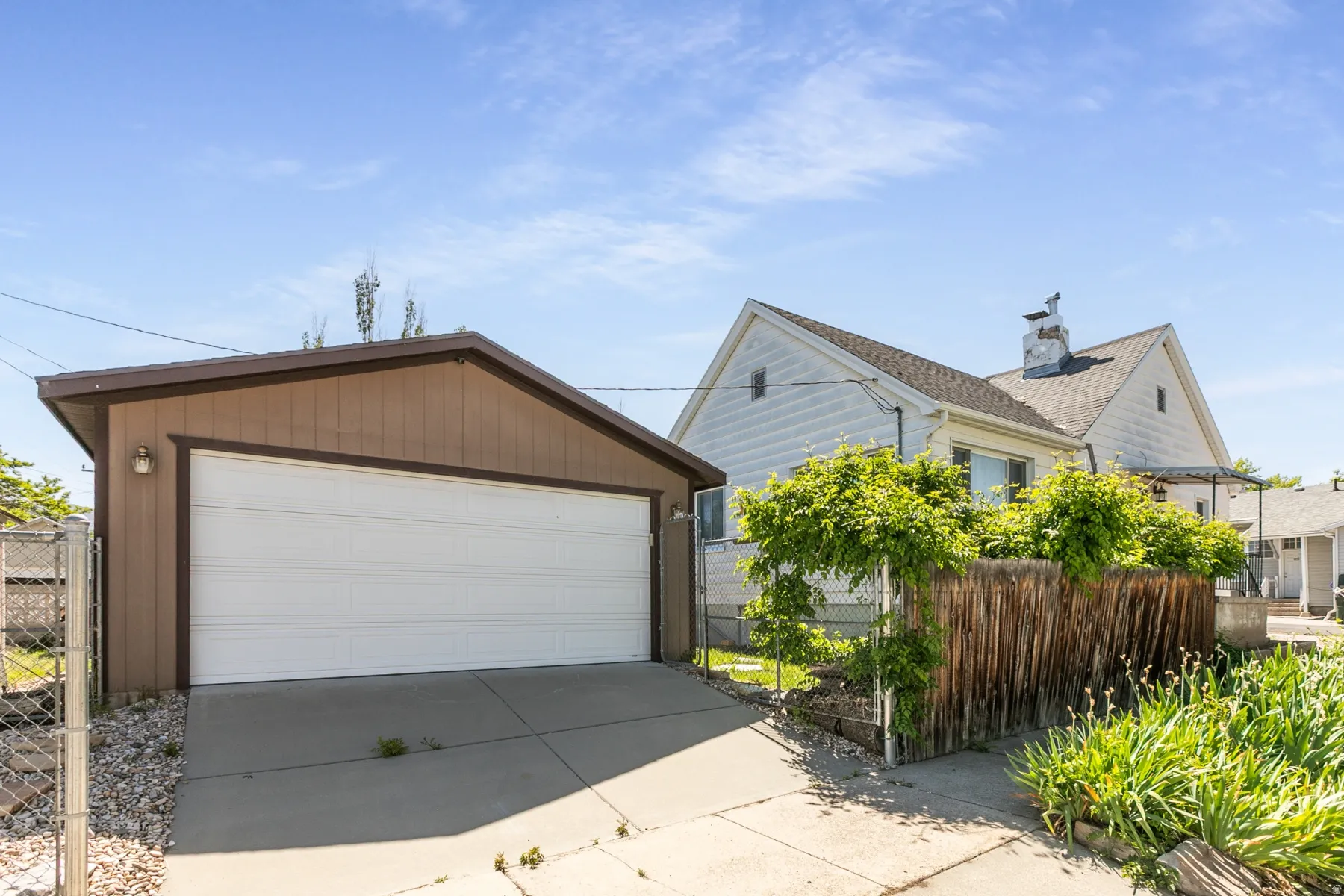 Detached garage with a white overhead door and brown siding