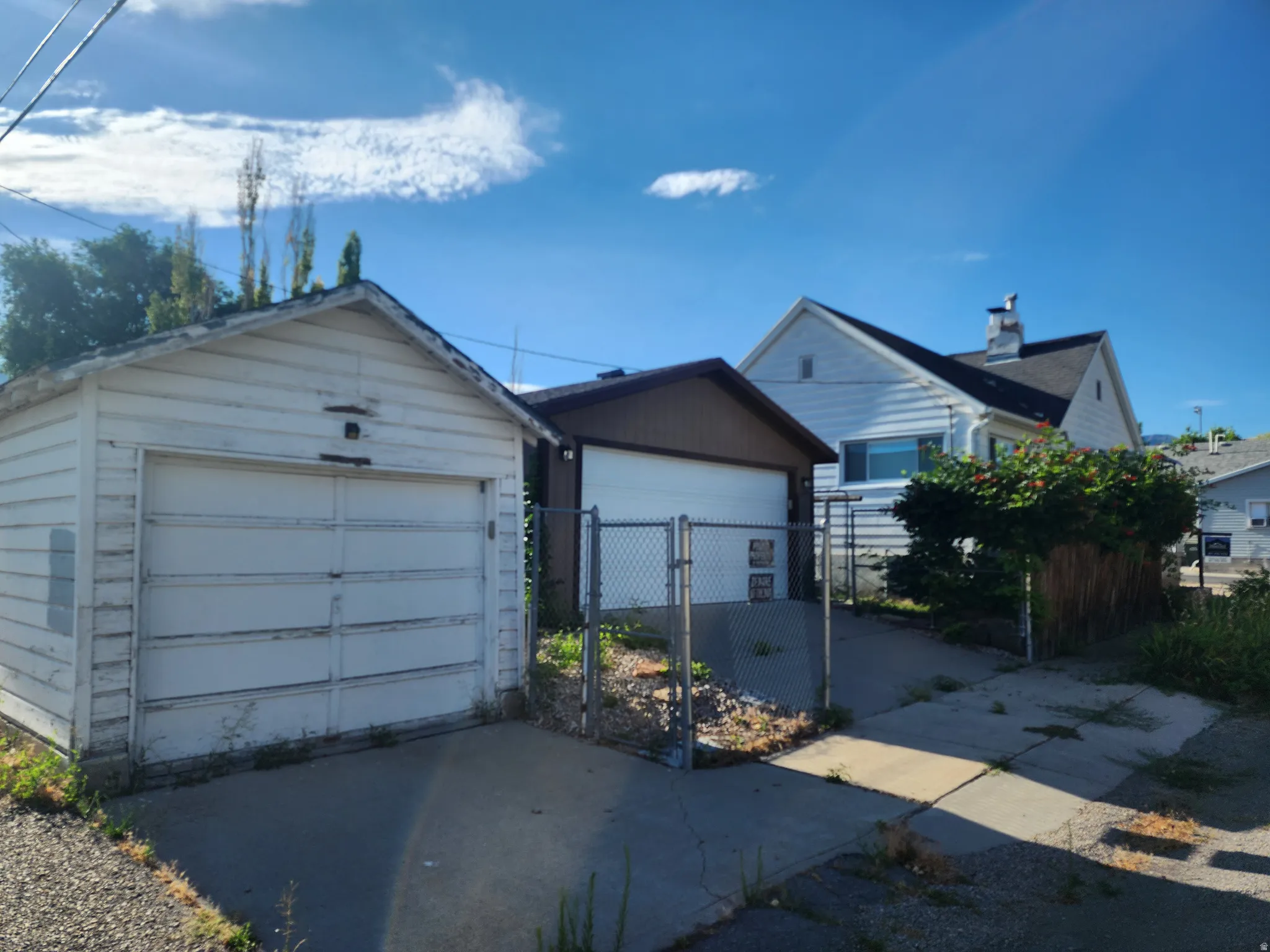 Detached garage with horizontal siding, concrete driveway, and chain-link fencing
