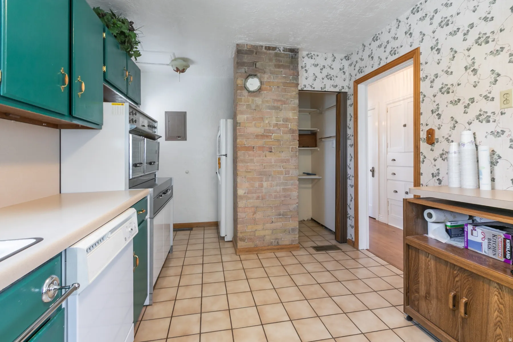Kitchen featuring tile flooring, green cabinetry, a built-in oven, and a brick accent wall