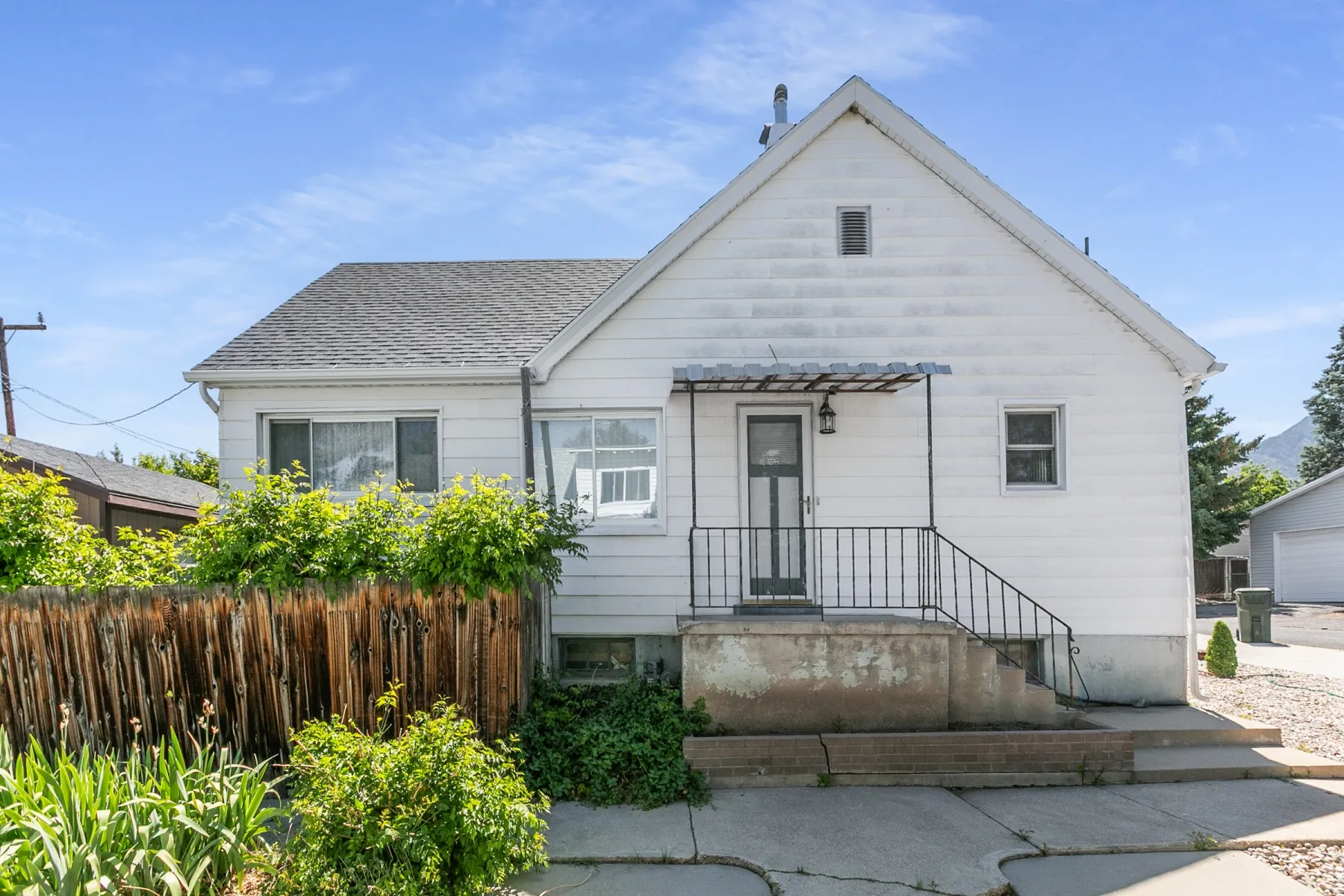 White siding exterior with a dark shingle roof and a covered entryway