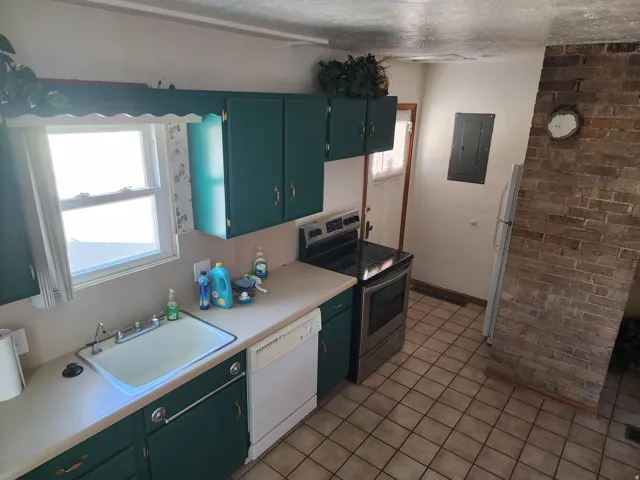 Kitchen featuring green cabinetry, a double basin sink, and a four-burner electric range