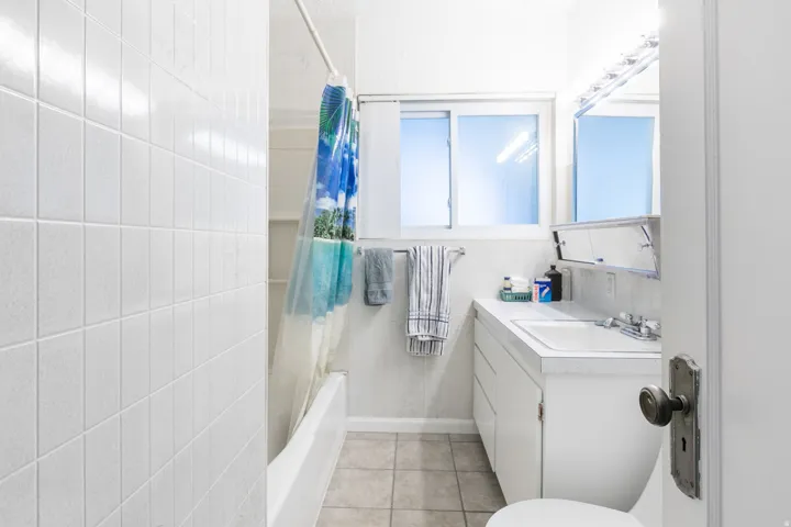 Bathroom featuring a white subway tile shower surround, a built-in bathtub, a window with frosted panes, a single vanity with storage, and a mirrored medicine cabinet