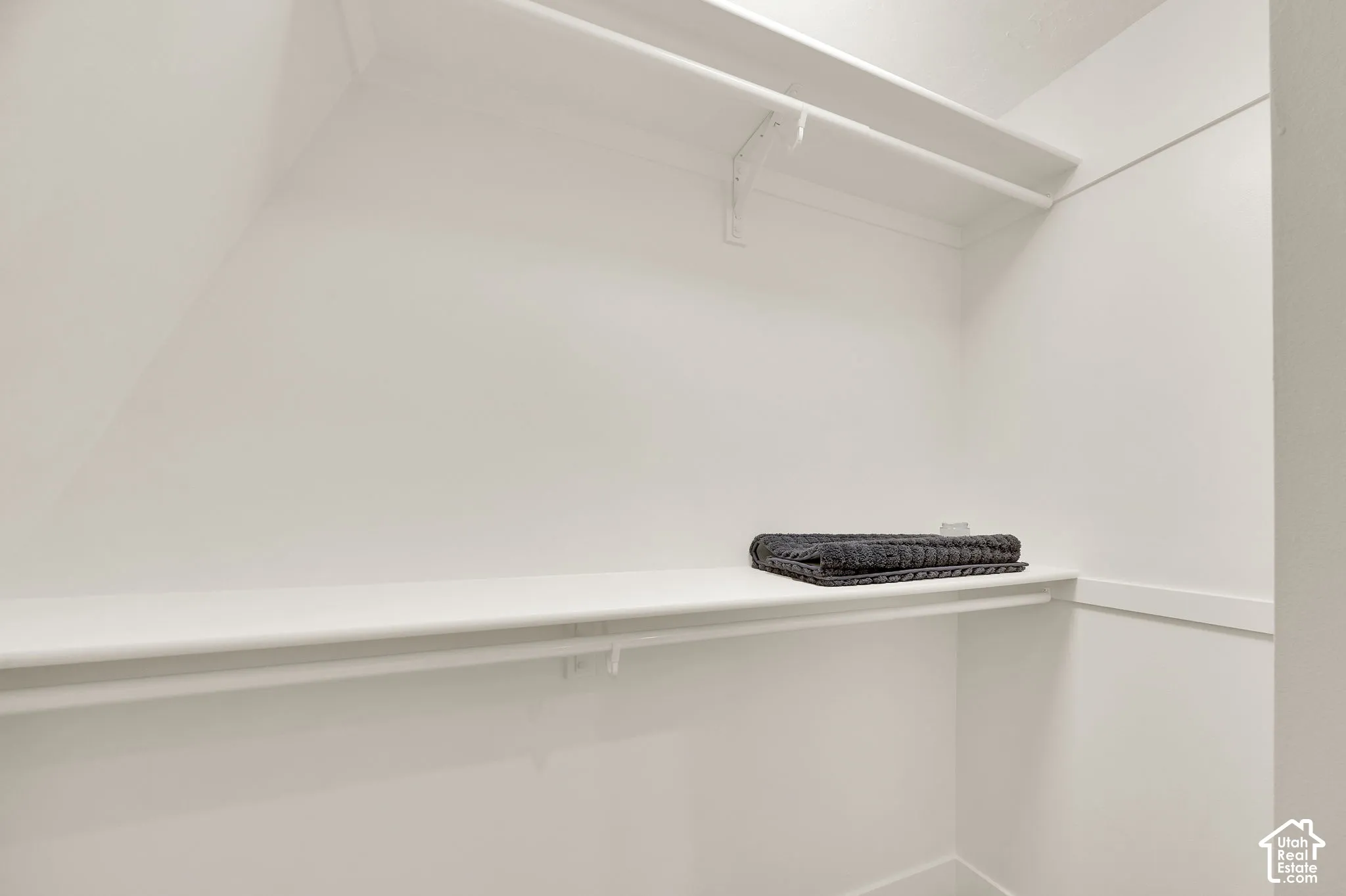 Corner closet featuring white shelving and a hanging rod