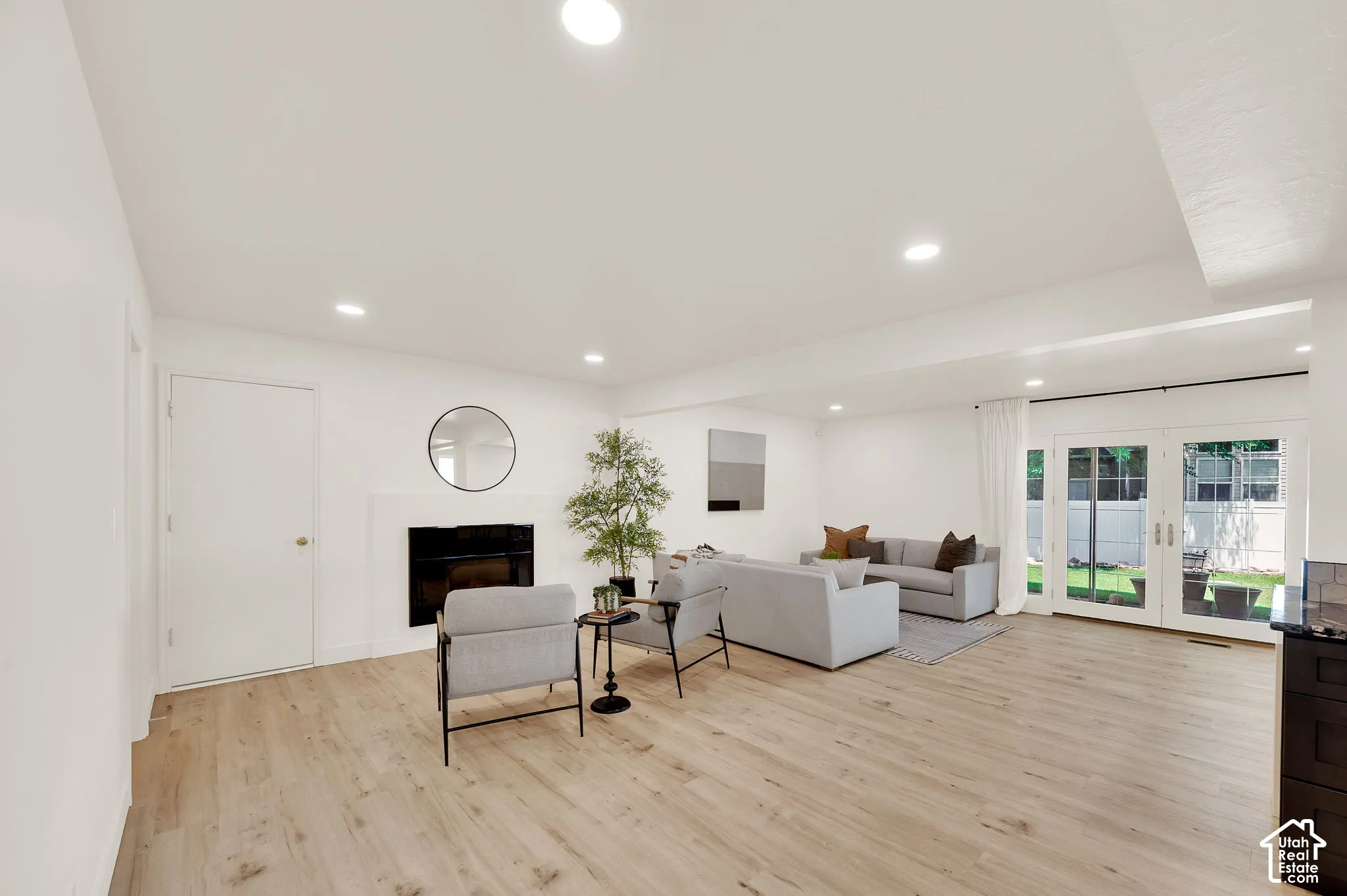 Spacious living area featuring wood-finish flooring, recessed lighting, and a white mantel fireplace