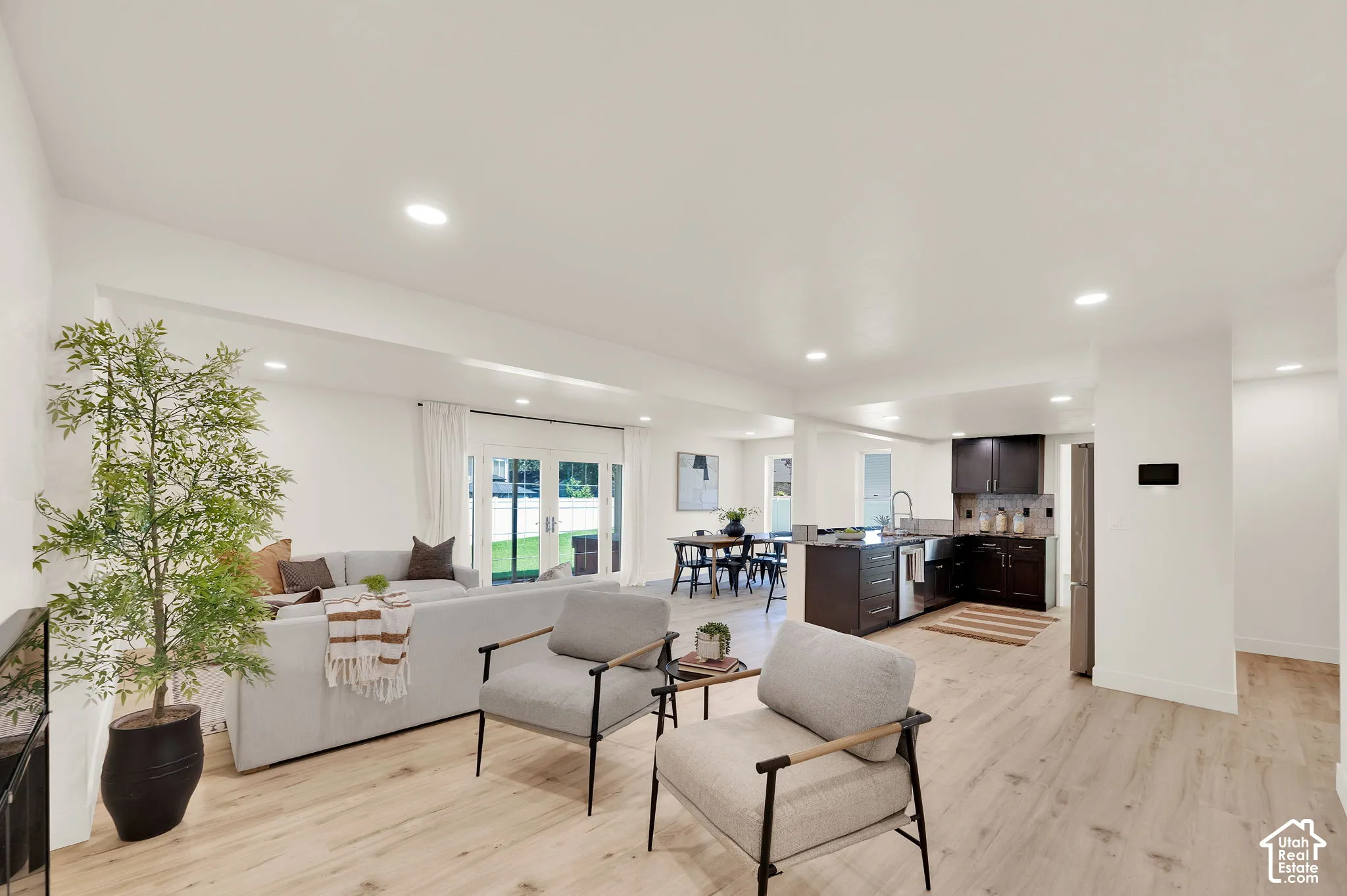 Open-concept living area featuring light wood-finish flooring, recessed lighting, and white walls