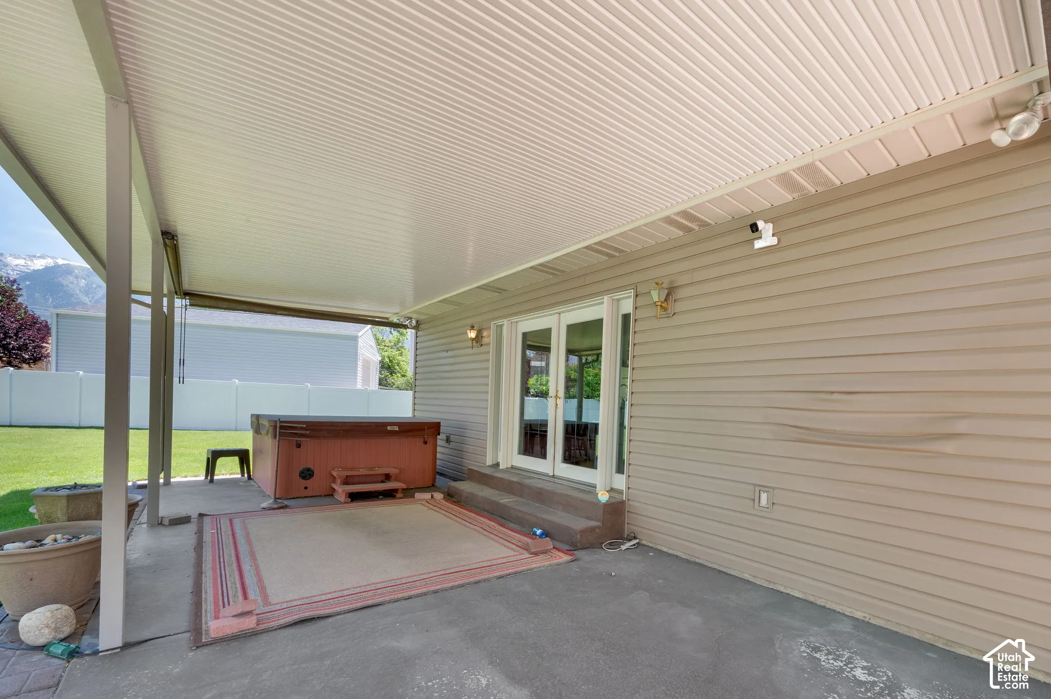 Covered patio featuring a solid roof structure, concrete flooring, and direct access through a set of French doors