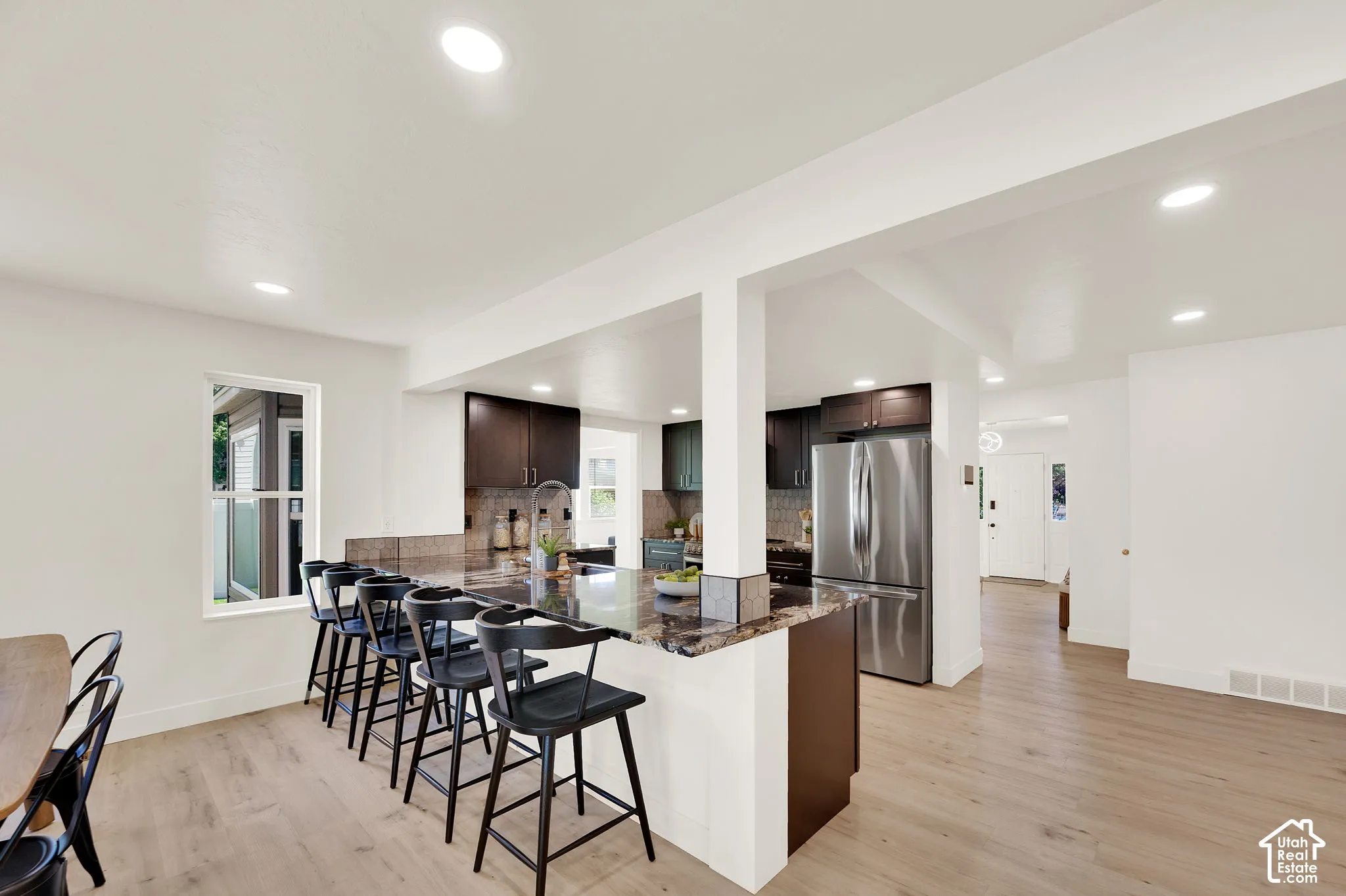 Kitchen featuring dark wood cabinetry, stainless steel refrigerator, and an island with a stone countertop and seating for five