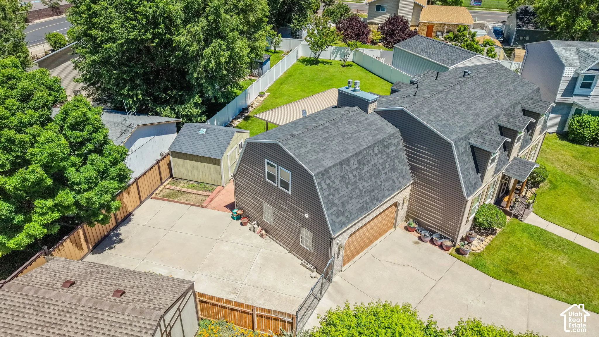 Dormer roofline home with attached garage, concrete driveway, and established landscaping