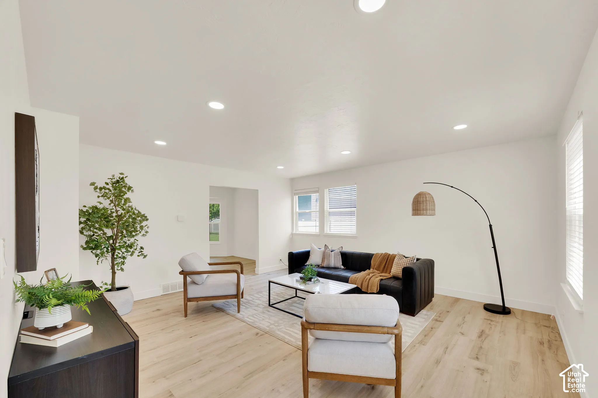 Bright living area featuring wood-finish flooring, recessed lighting, white walls, and multiple windows with blinds
