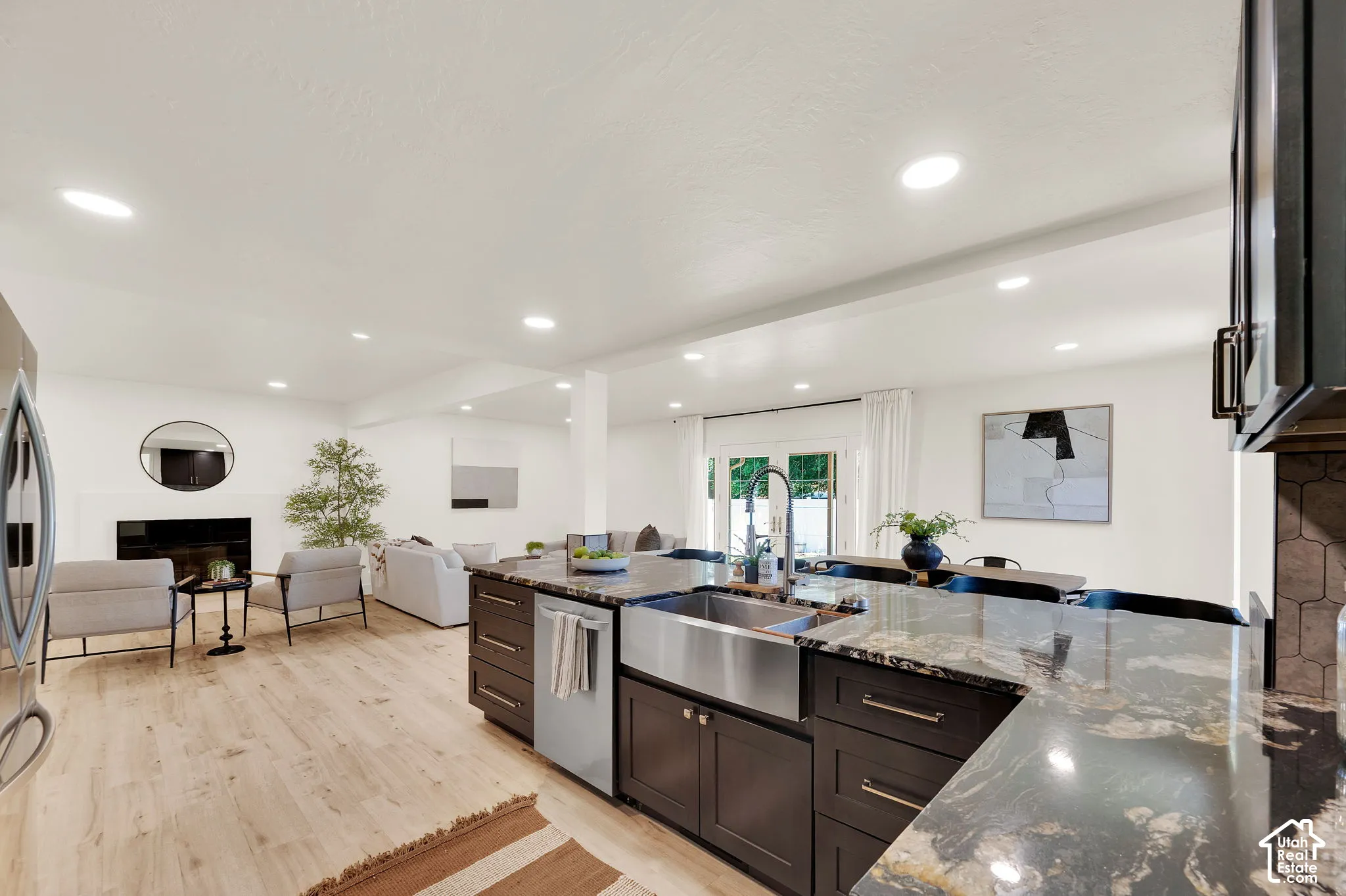 Spacious kitchen island featuring a farmhouse sink, dark wood cabinetry, and a granite countertop