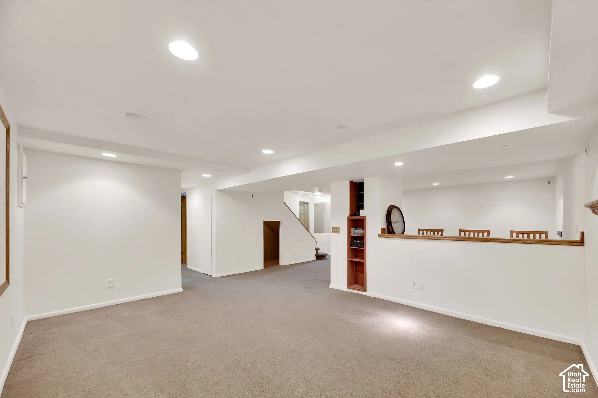 Expansive lower level featuring neutral carpeting, recessed lighting, white painted walls, and built-in shelving
